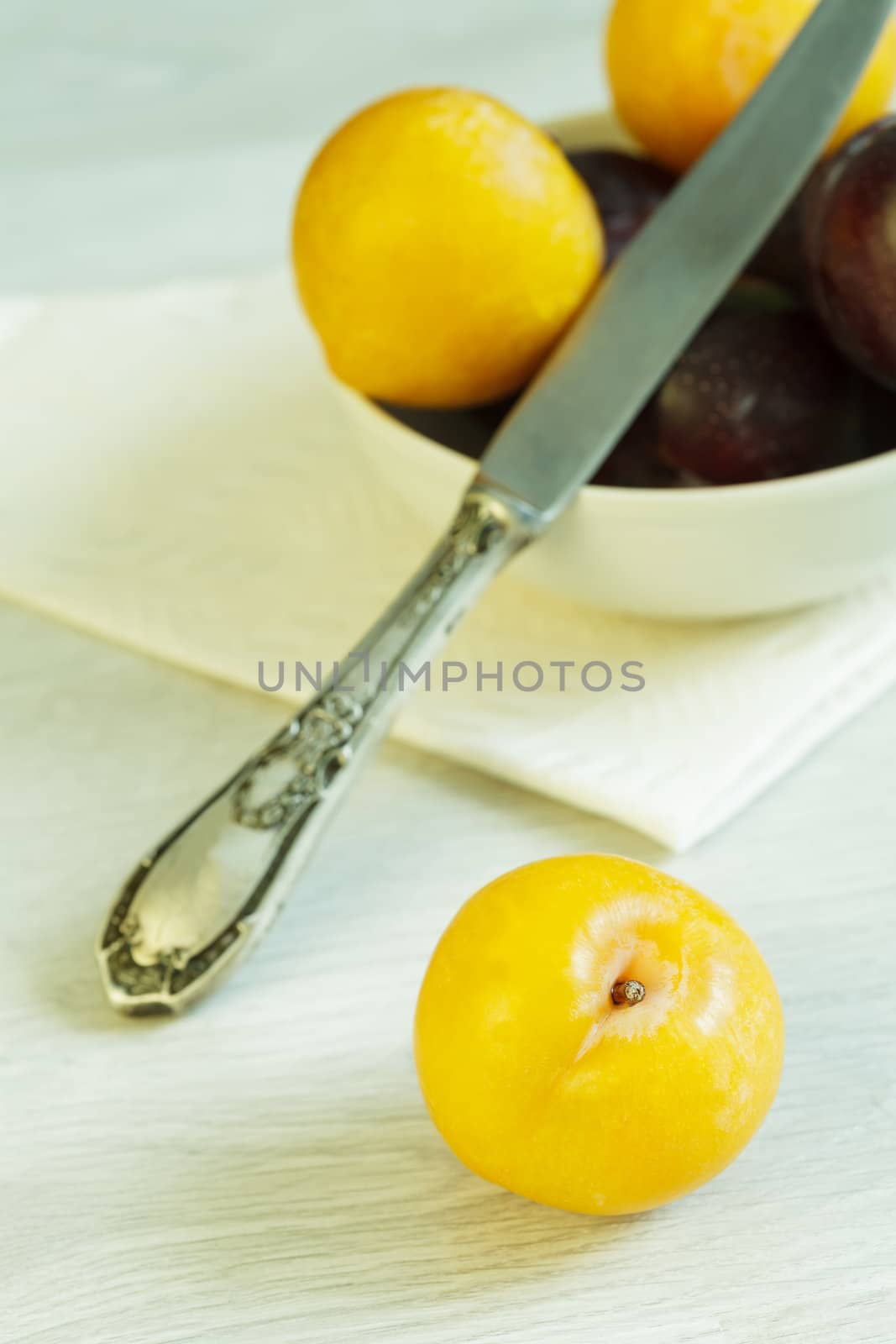 Many plums and knife on the table