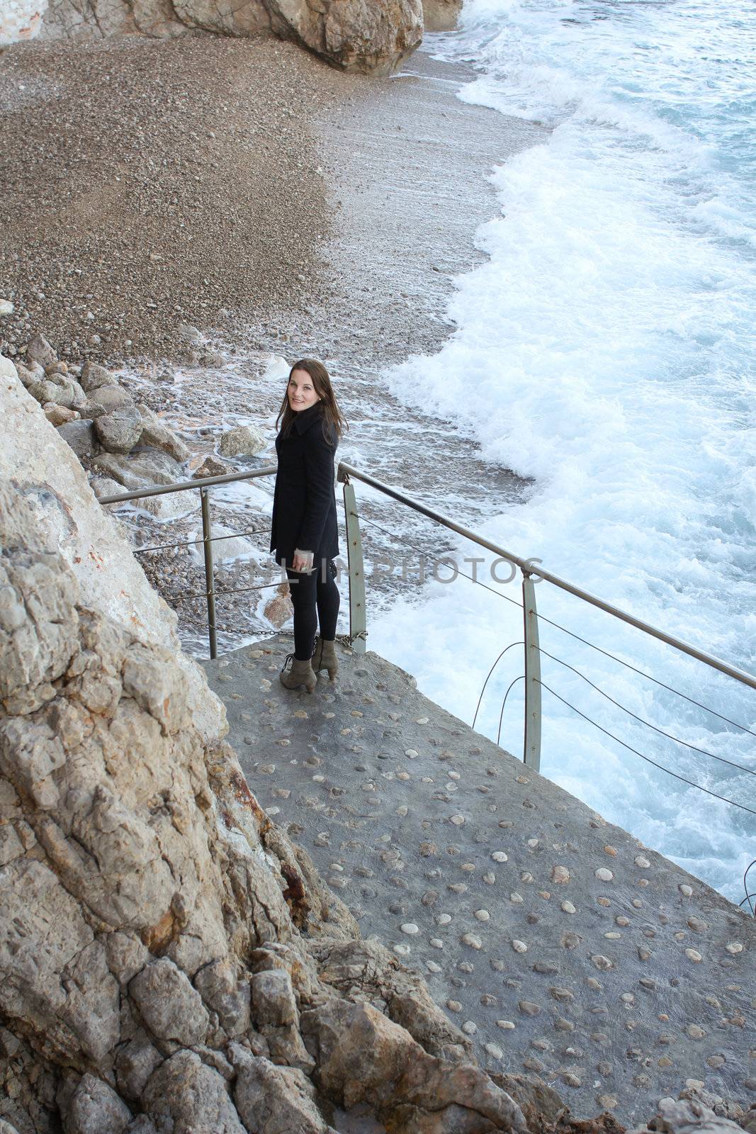 Woman standing in front of beach and wild sea