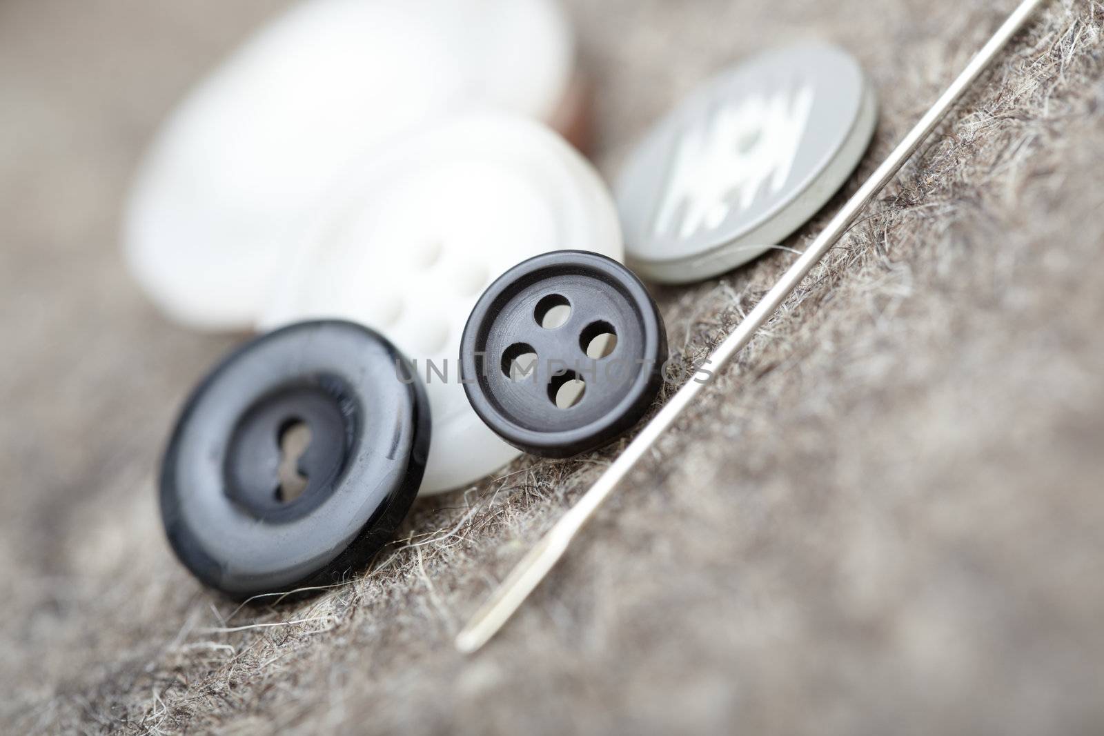 Buttons and sewing needle. Extremely close-up photo with shallow depth of field