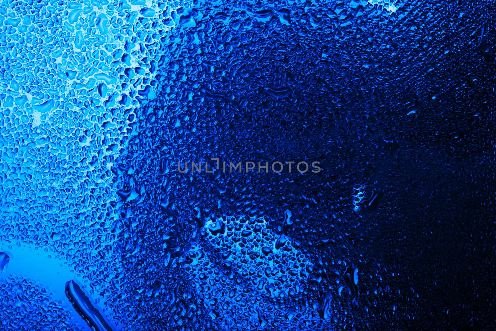 Wet glass with water drops in blue tone