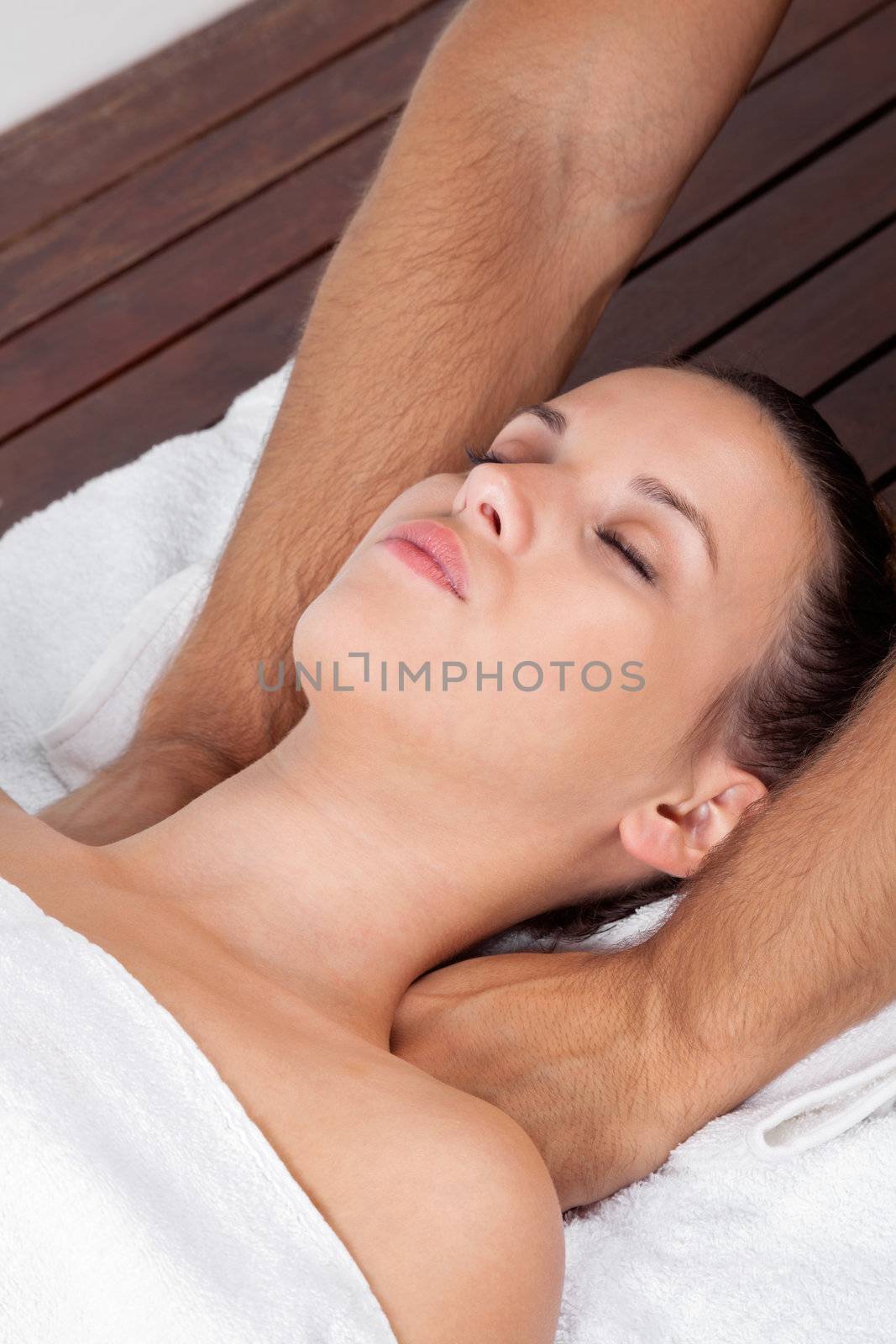 Pretty young female relaxing with eyes closed as she receives massage at health spa