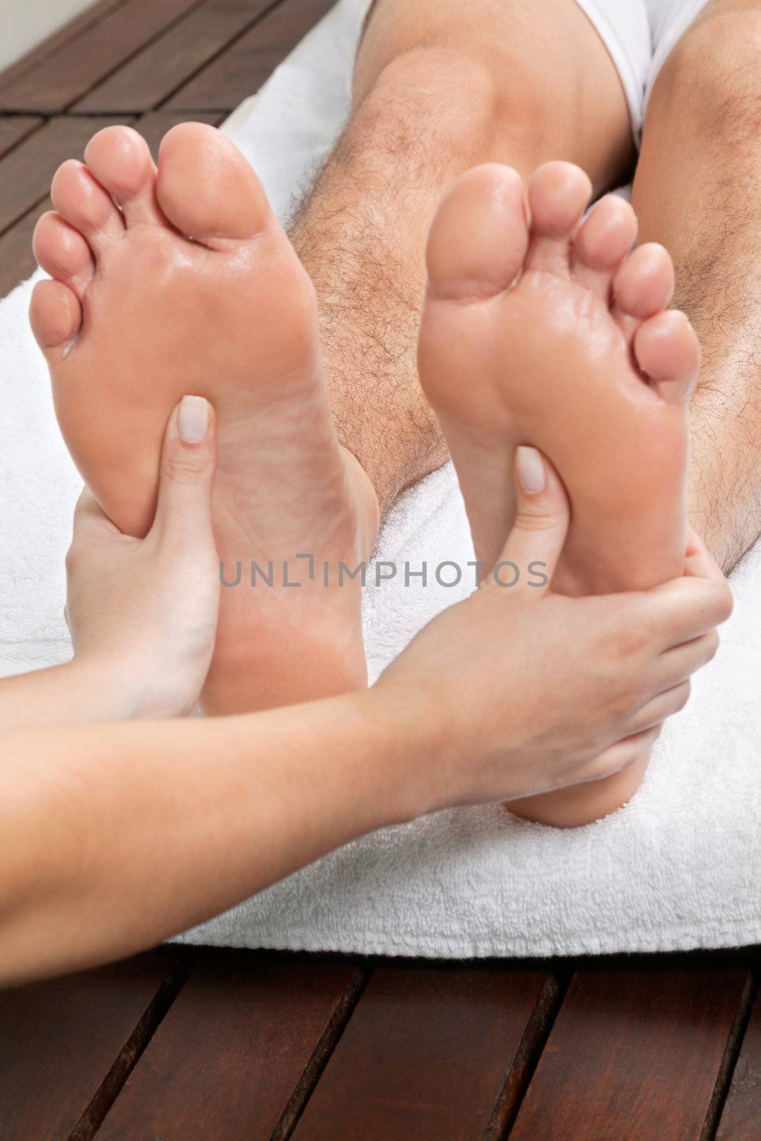 Close up of female masseuse giving foot massage to male's bare foot