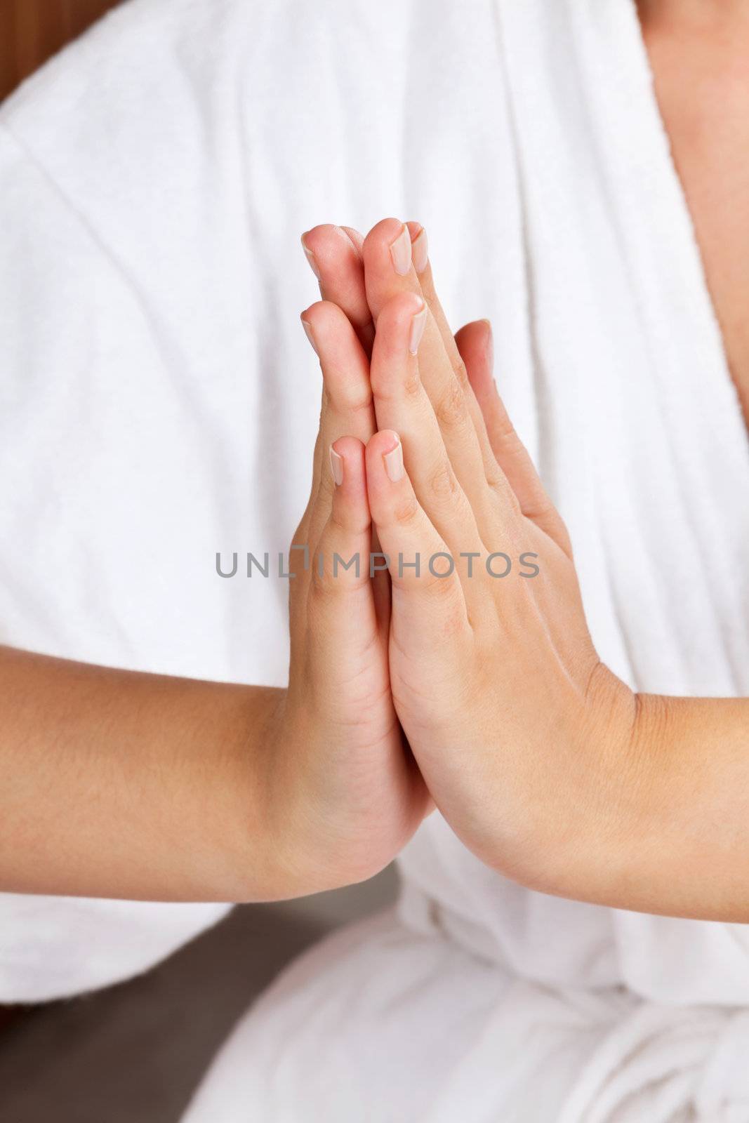 Midsection of a female in white bathrobe meditating with hands clasped