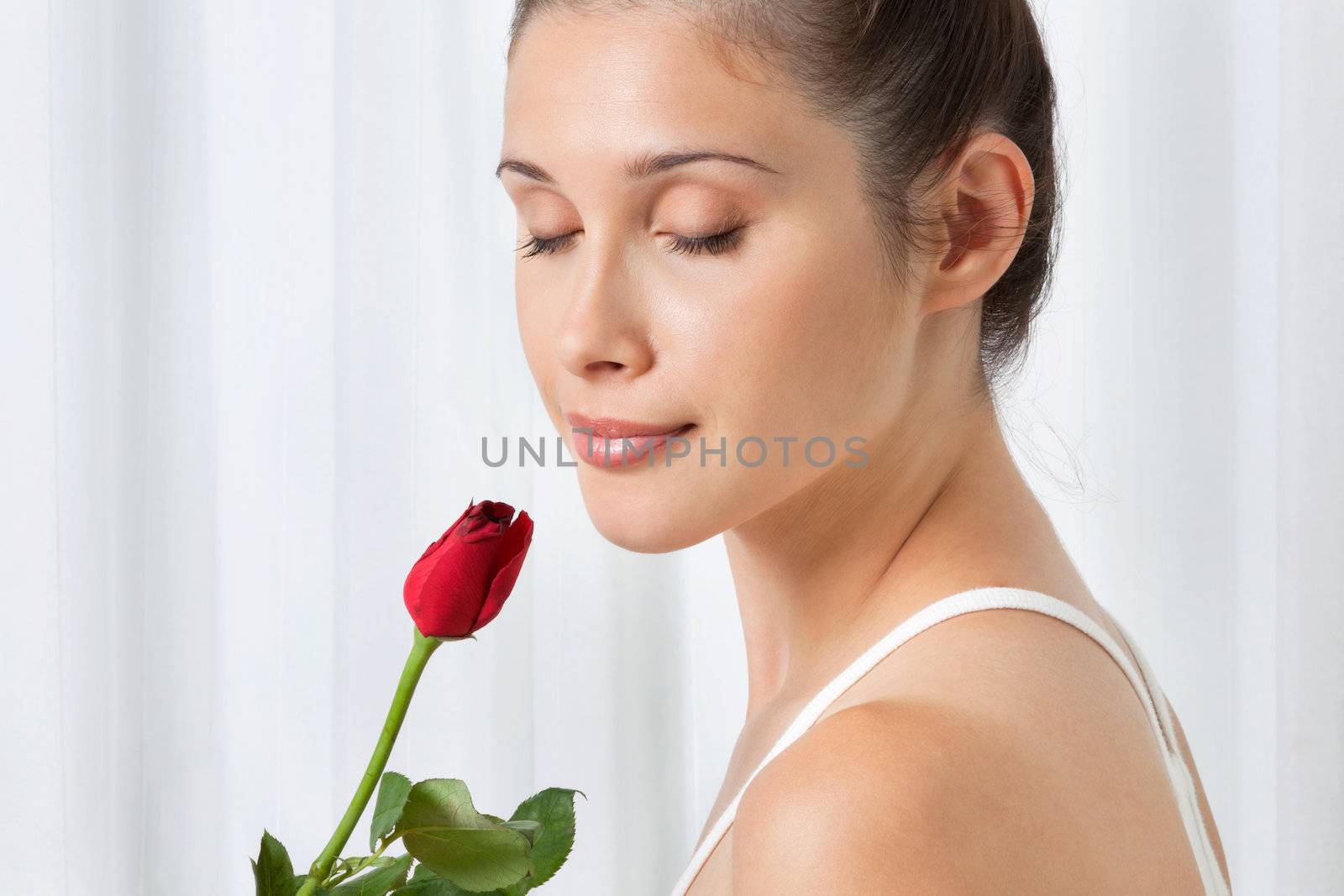 Beautiful calm young woman holding a red rose over white background