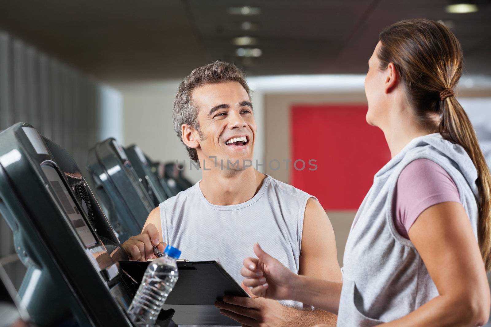 Happy Instructor Looking At Female Client Exercising On Treadmil by leaf
