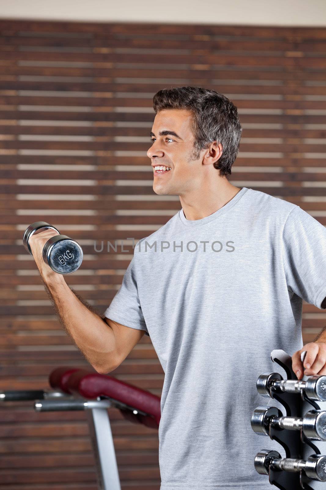 Man Lifting Dumbbell In Health Center by leaf