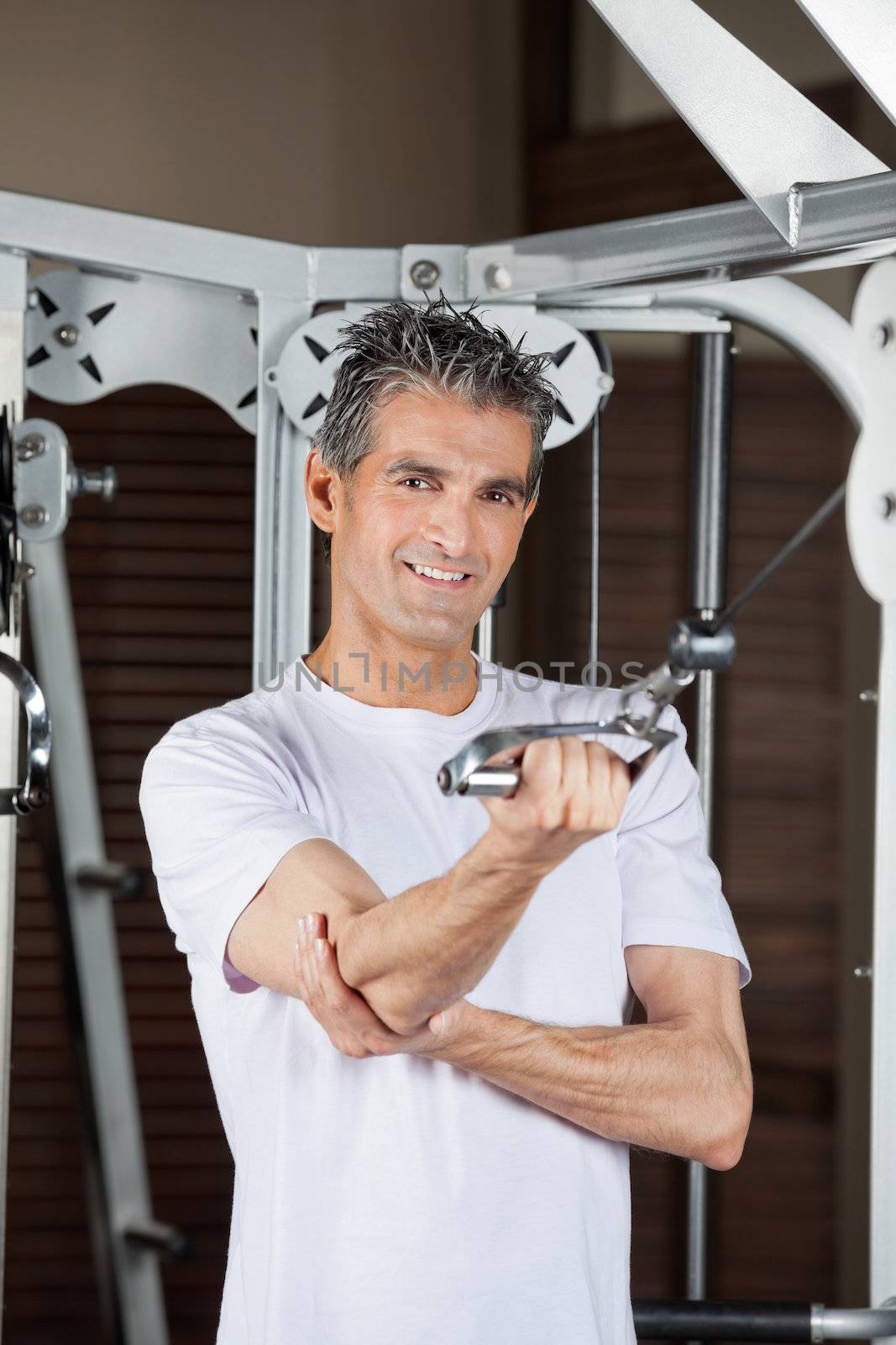 Portrait of happy mature man working out in fitness center