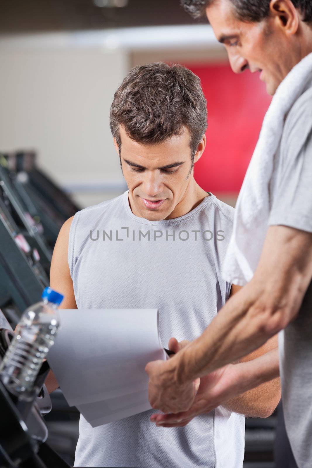 Male instructor making notes on clipboard in health club