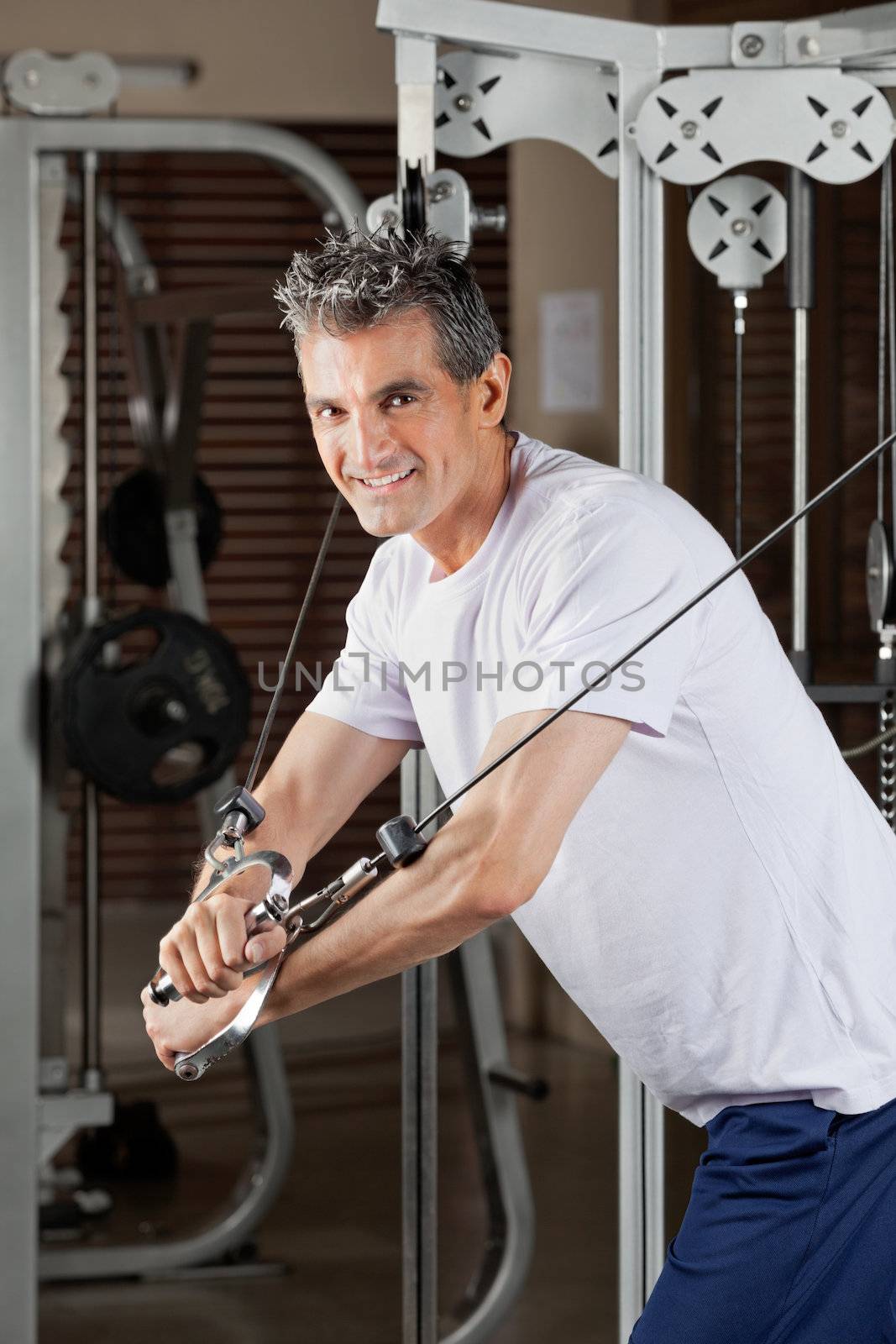 Mature Man Working Out In Fitness Center by leaf