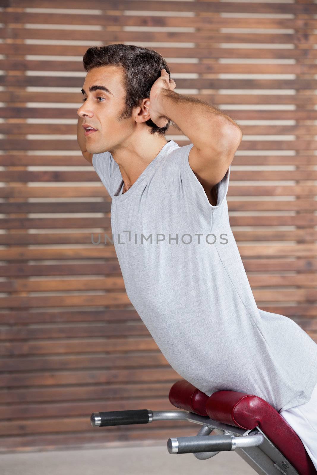 Side view of young man exercising on machine in health club