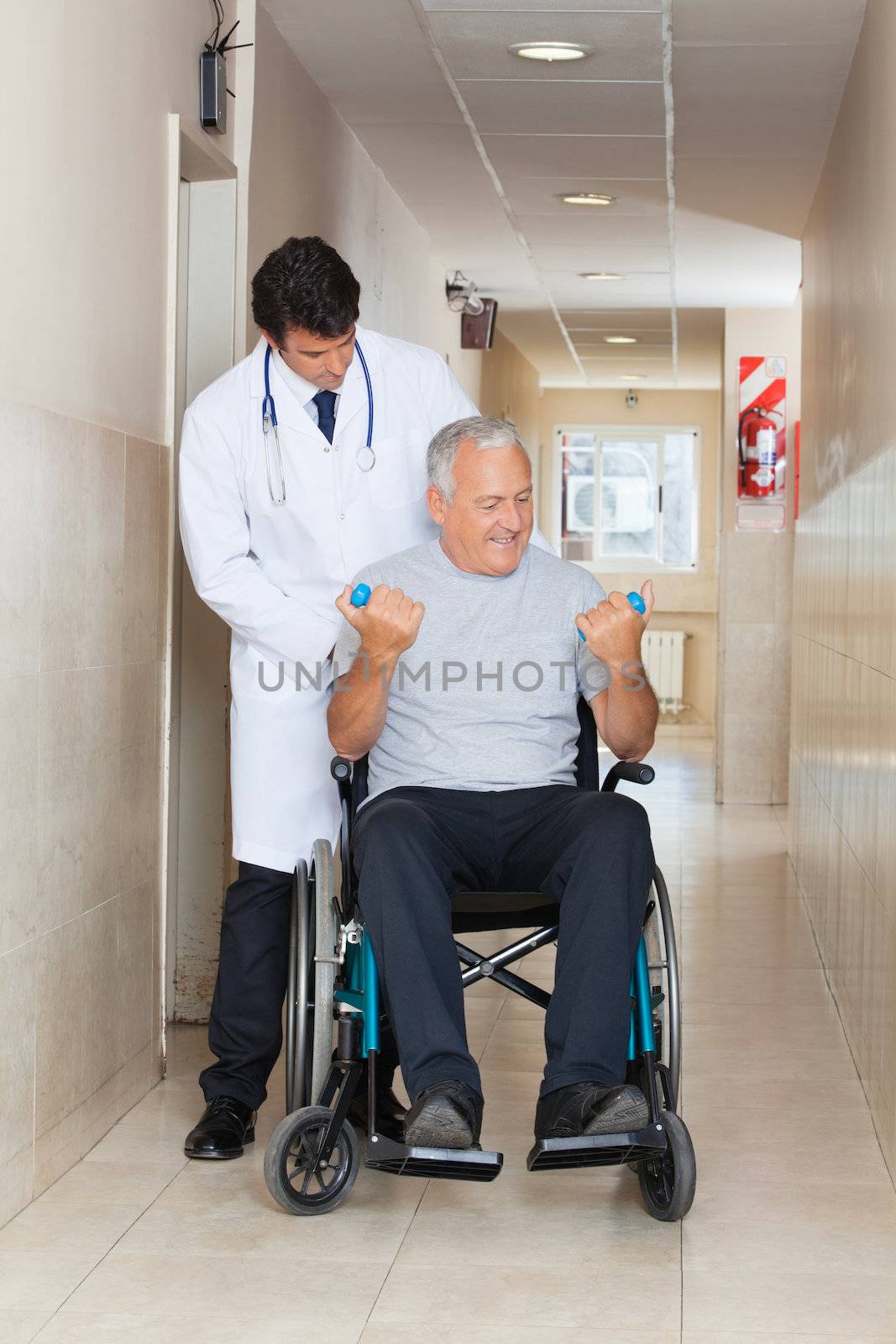 Doctor giving muscle training to the senior man sitting in a wheelchair