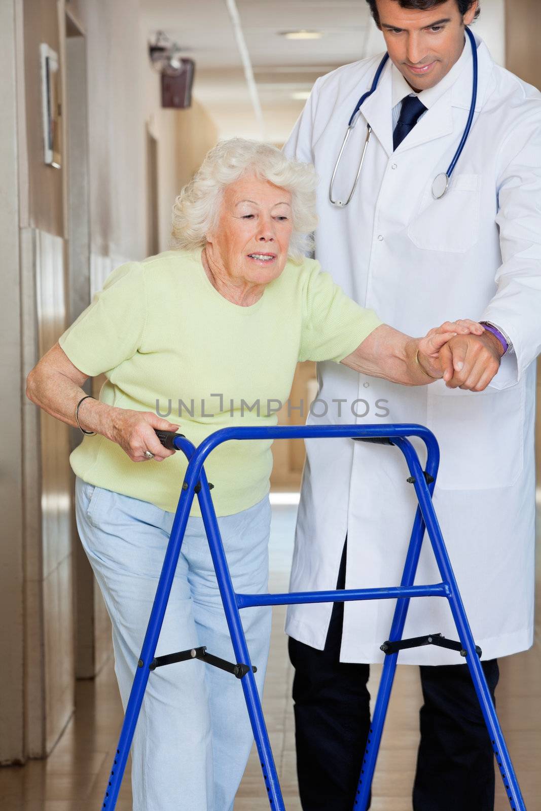 Young male doctor showing way to the patient using walker