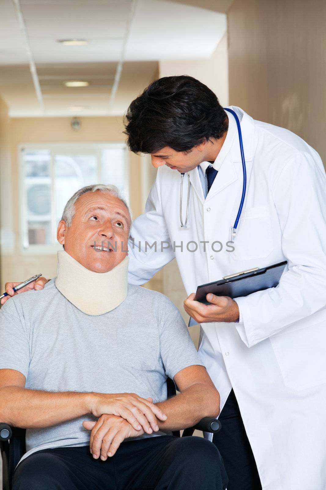 Friendly young doctor communicating with senior man sitting in wheel chair