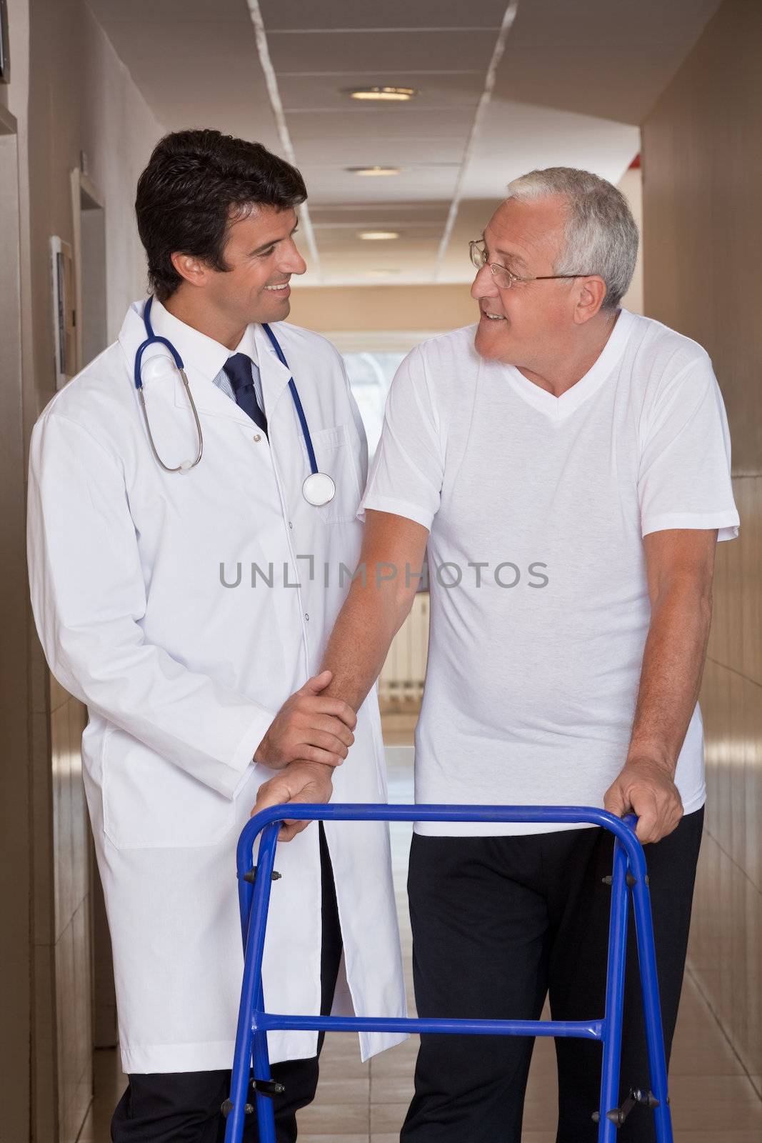 A doctor assisting a senior citizen onto his walker.