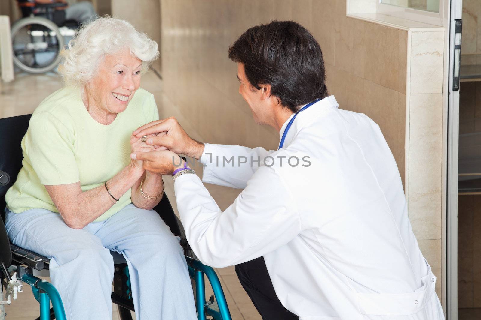 Young doctor comforting happy senior woman in hospital