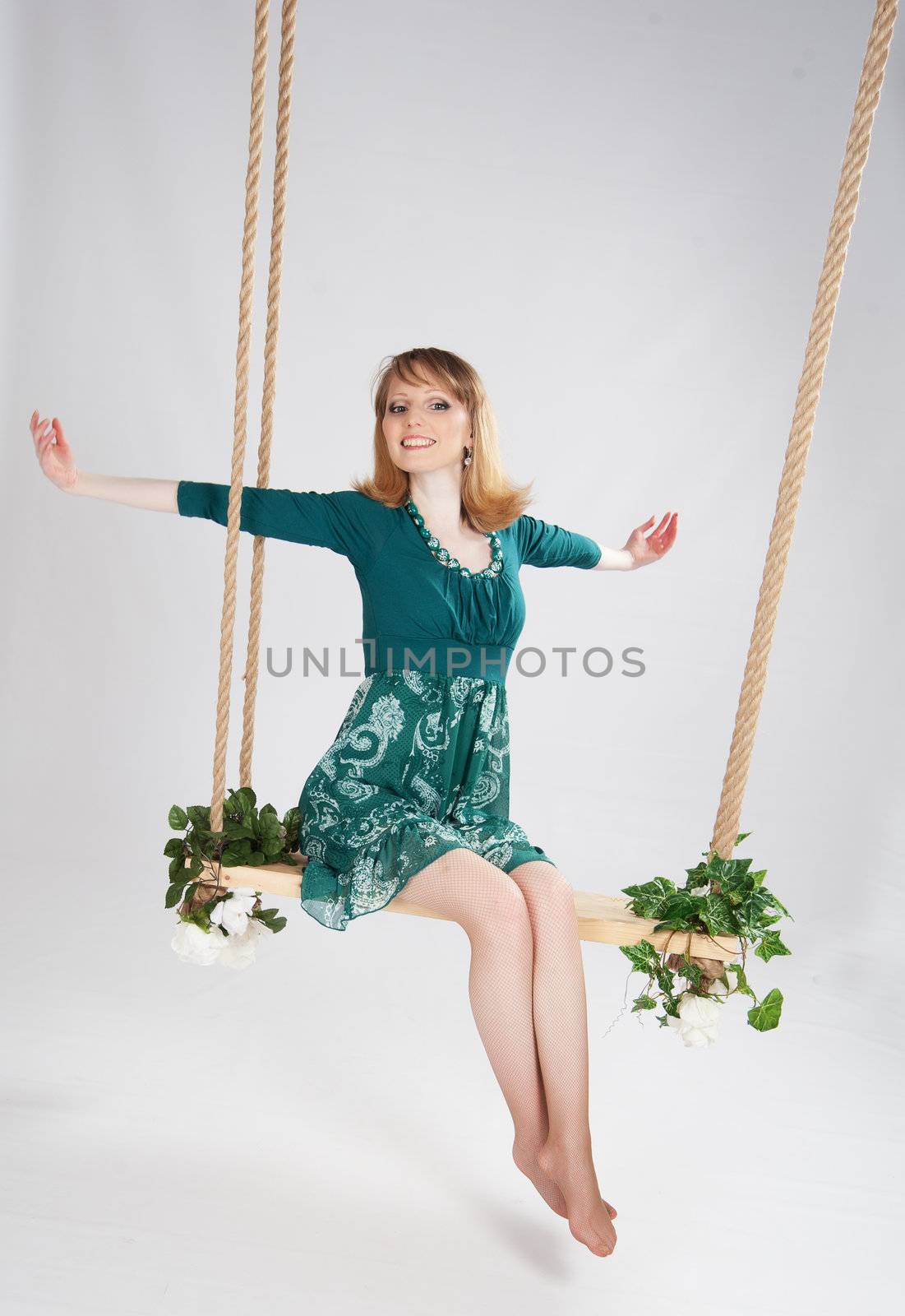 beautiful woman in a green dress on a swing