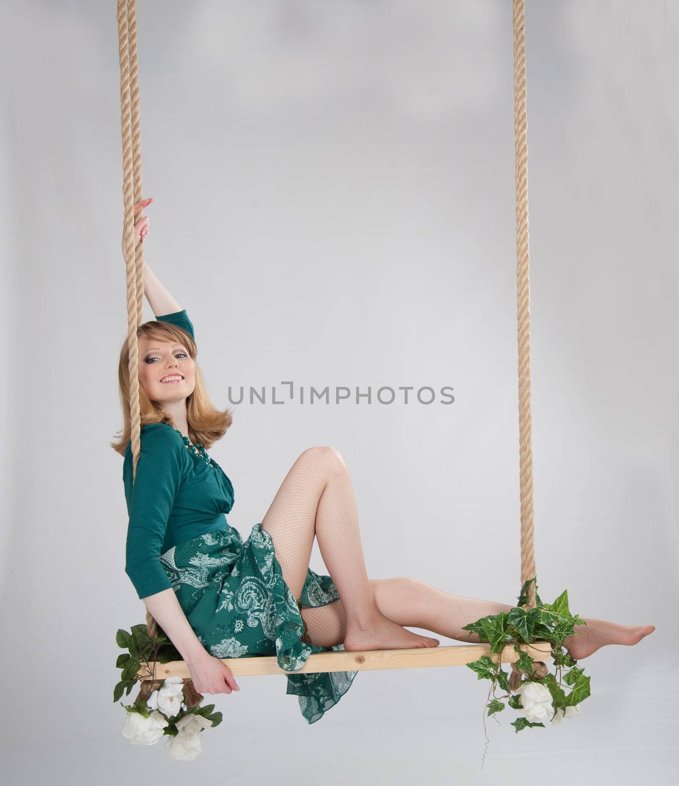 beautiful woman in a green dress on a swing