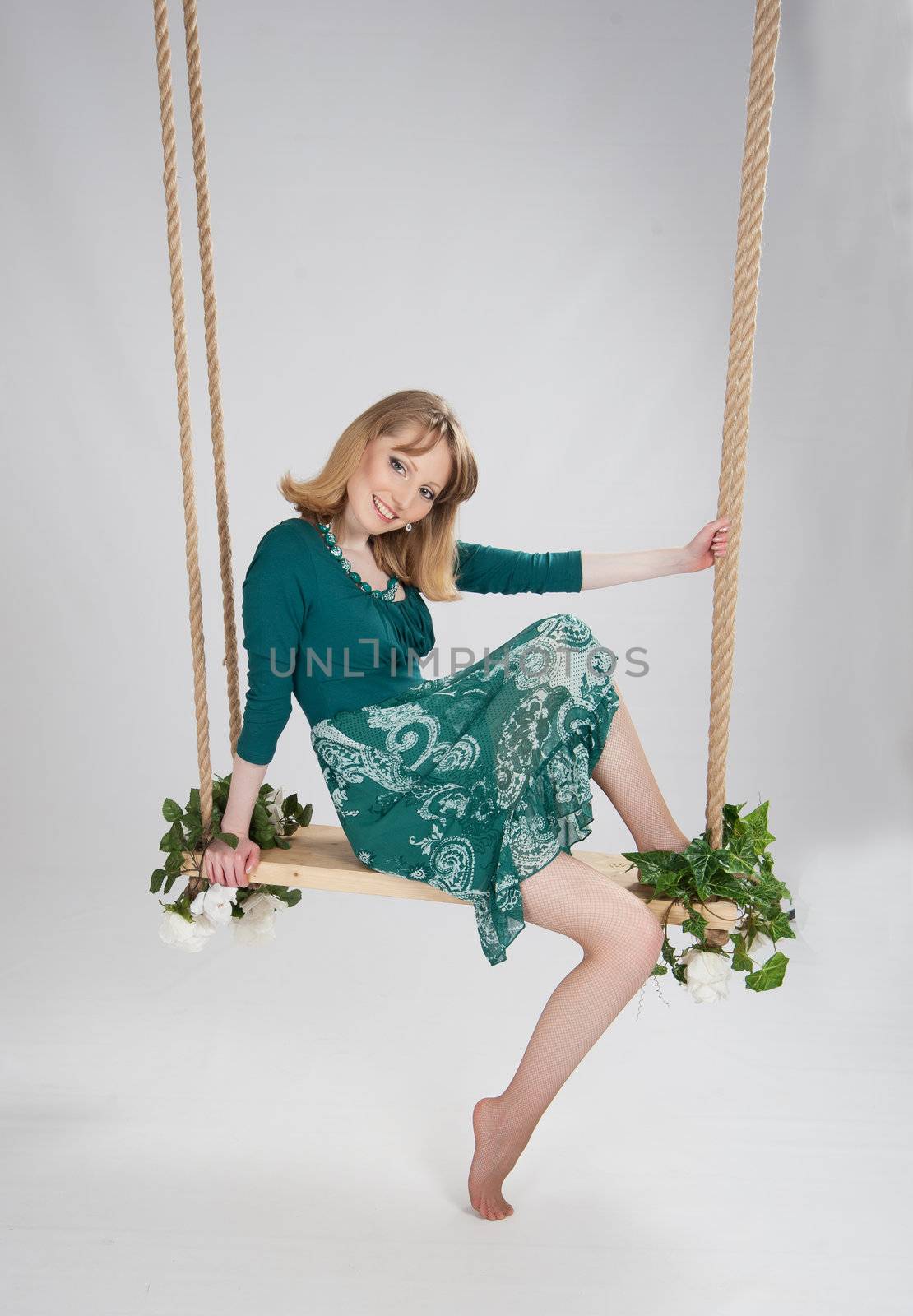 beautiful woman in a green dress on a swing