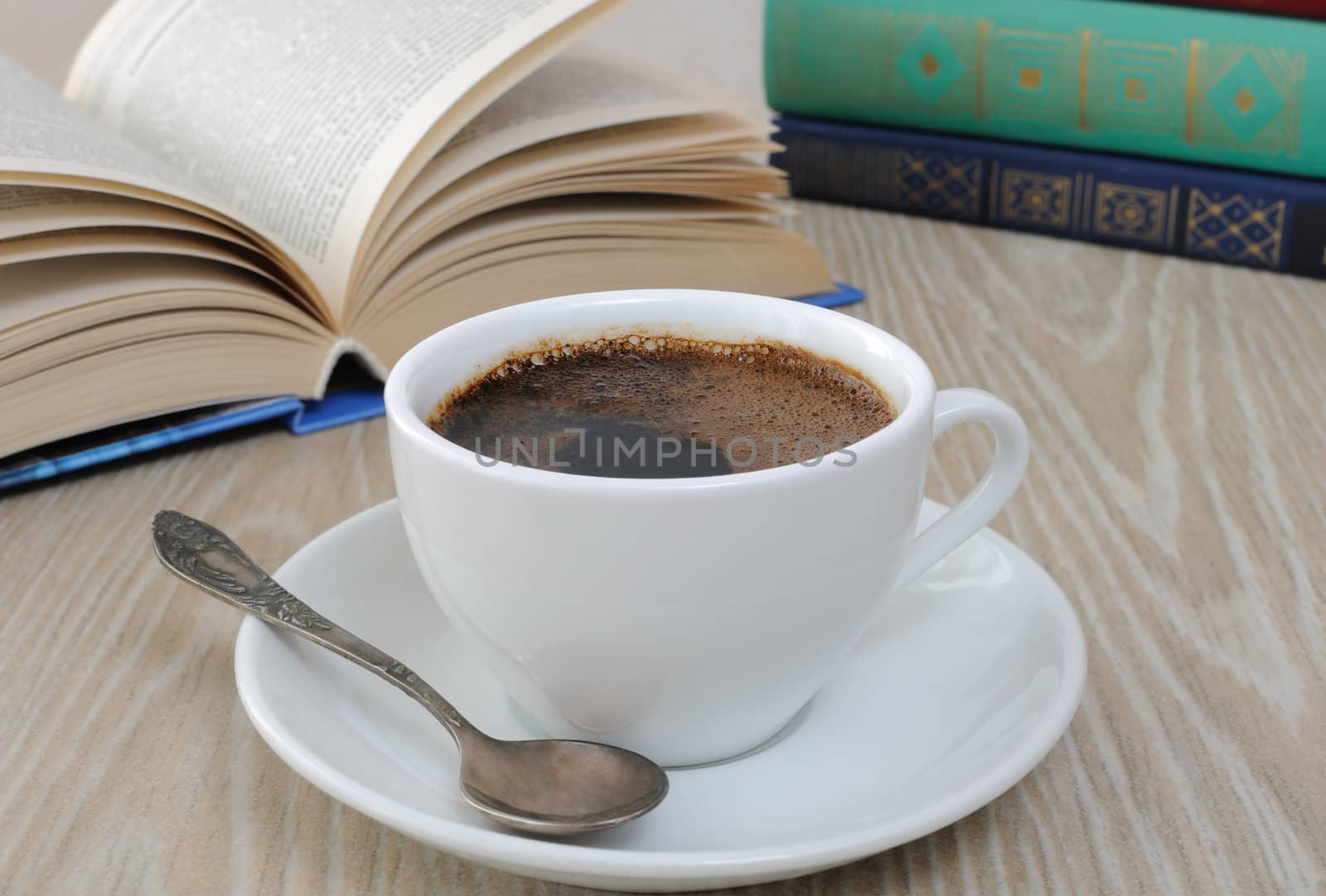 A cup of fragrant black coffee on the table against the background of an open book