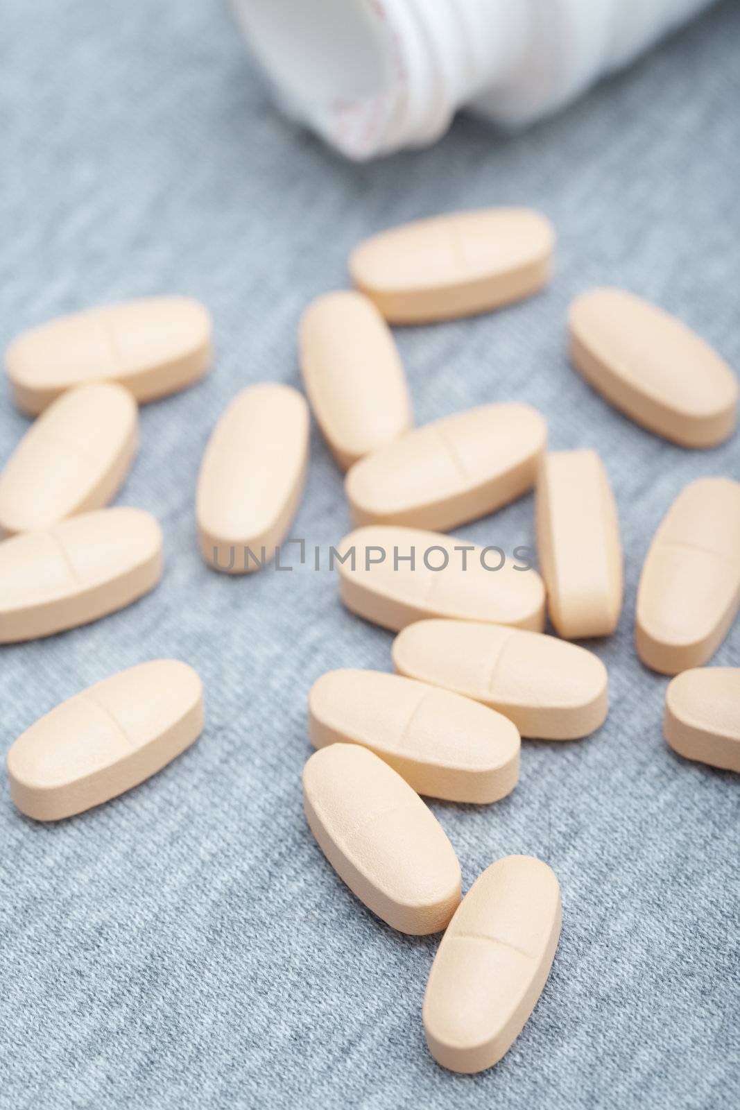 Many pills near white container. Close-up photo