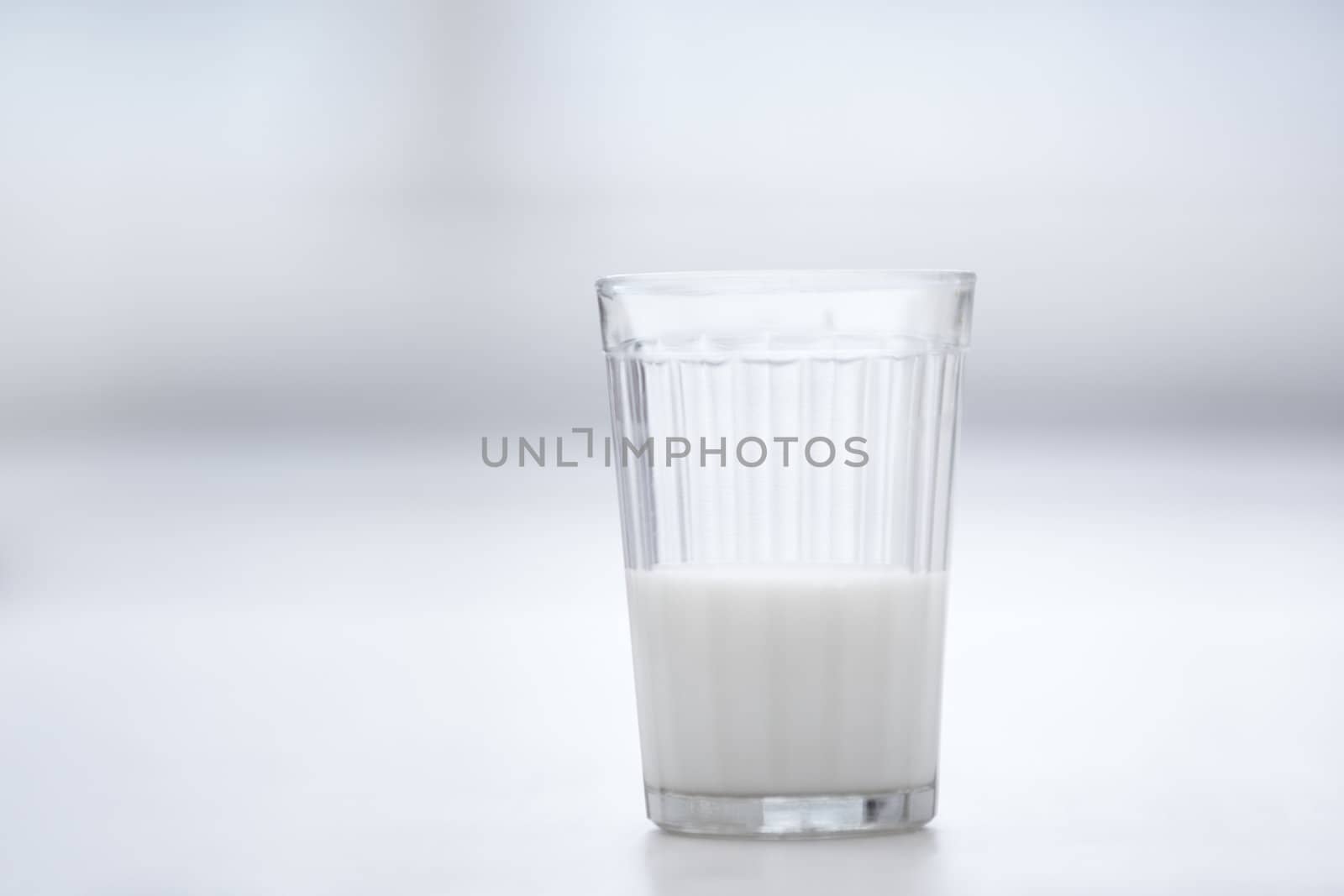 Glassful of milk on the table in white room