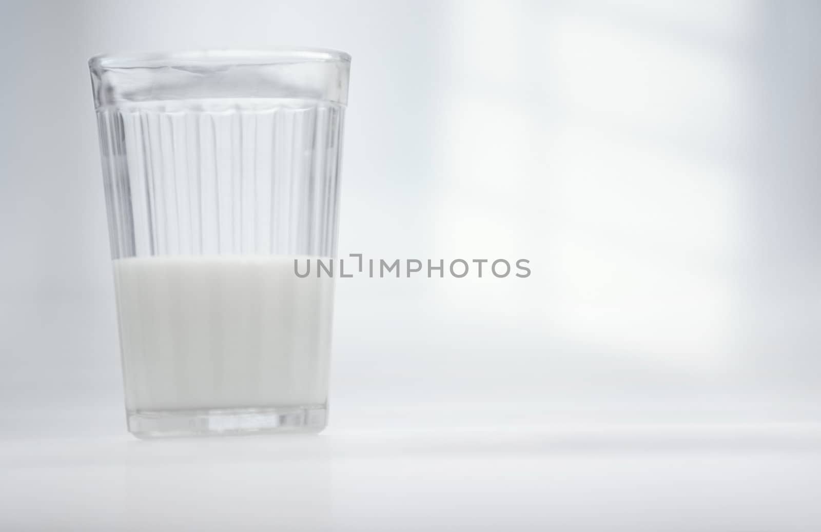 Glassful of milk on the table in white room
