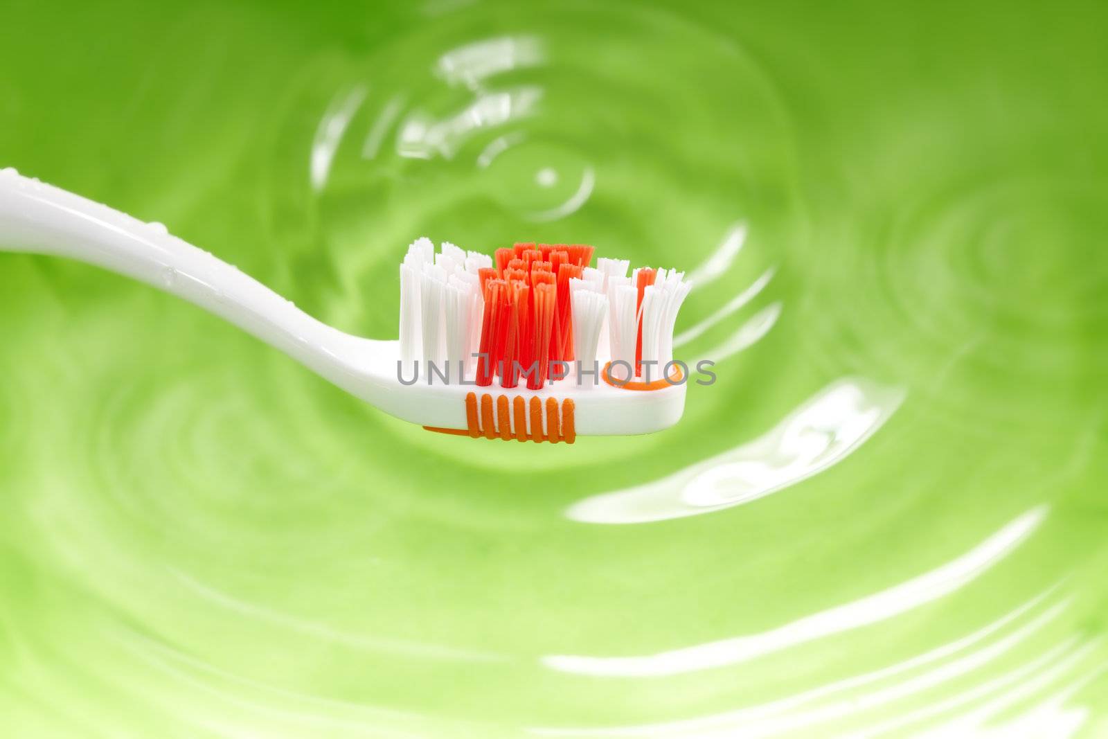 Close-up photo of the toothbrush on a green water background. Natural colors