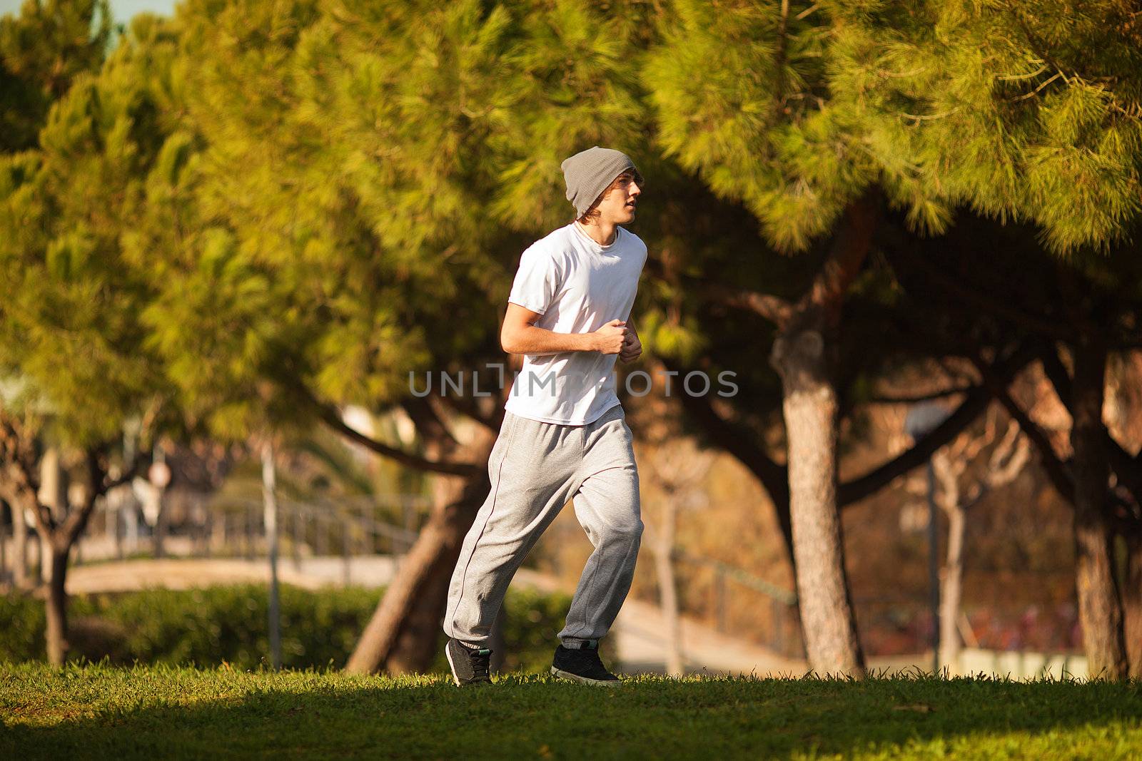 young handsome man jogging in public park by Lcrespi