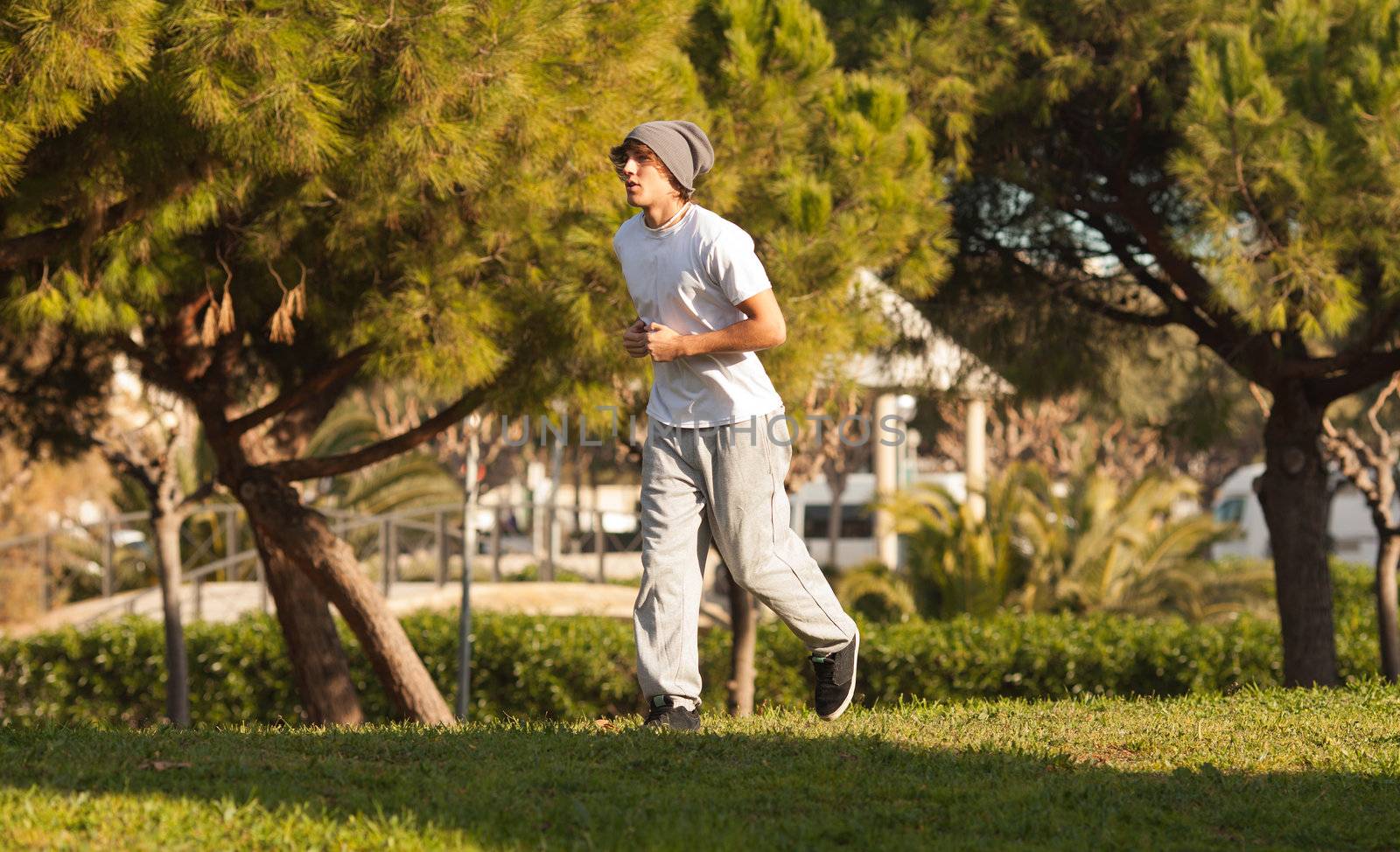 young handsome man jogging in public park by Lcrespi