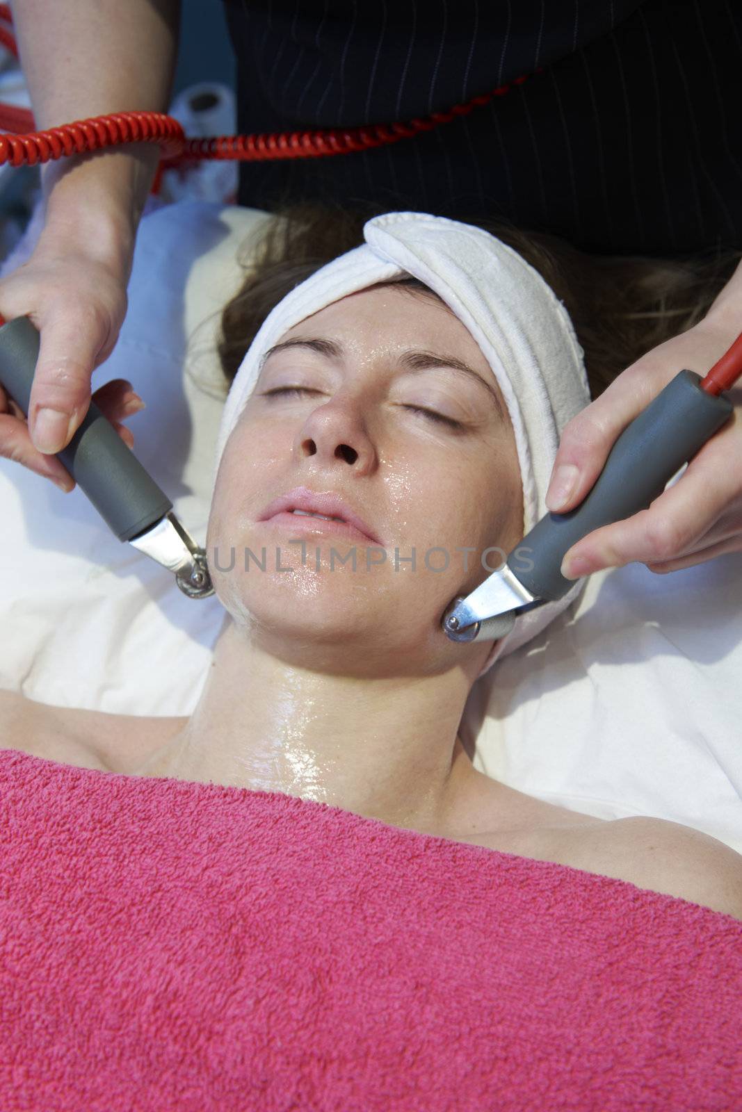 woman having a stimulating facial treatment from a therapist