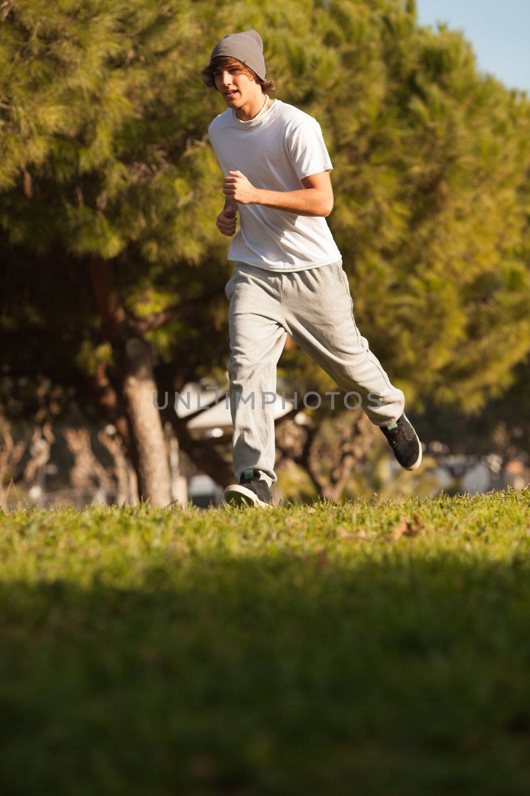 young handsome man jogging in public park by Lcrespi