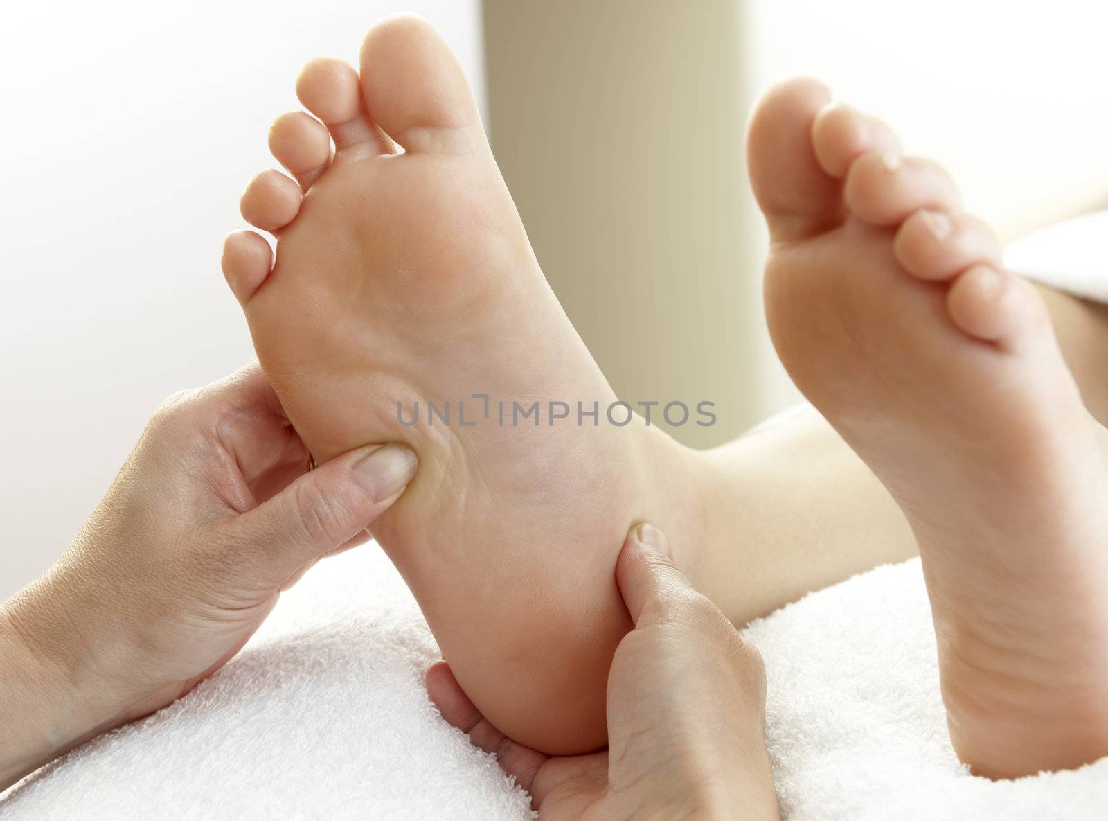 pair of feet being massaged by hands on white towel