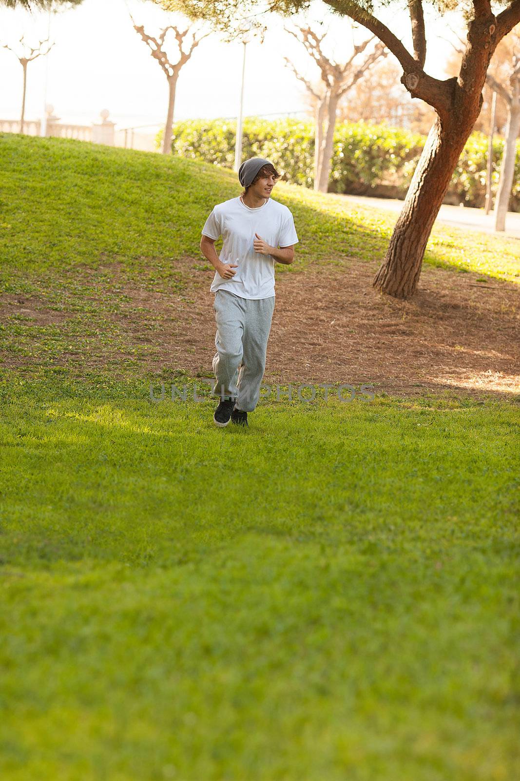 young handsome man jogging in public park by Lcrespi