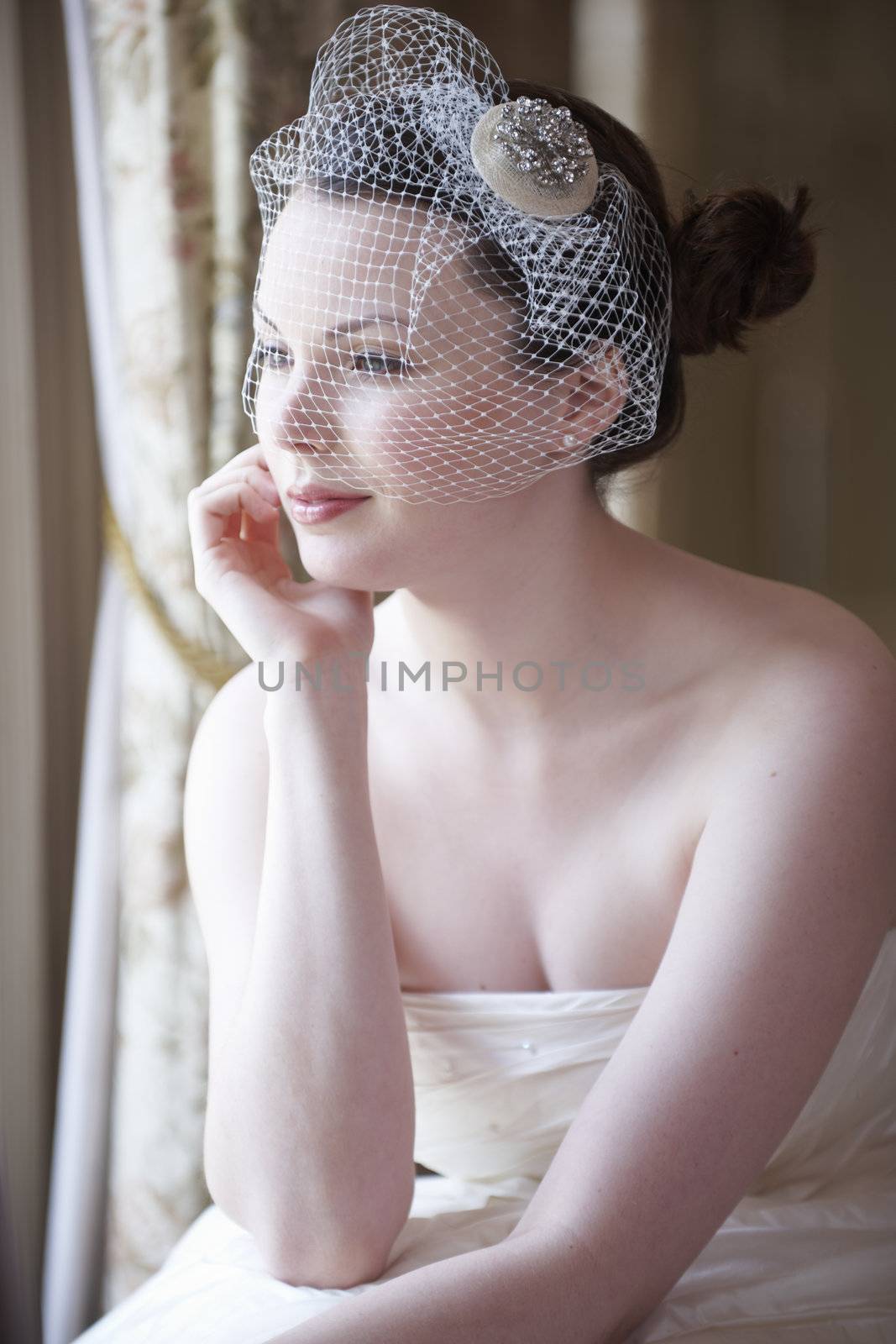 Pretty bride looking out of window and smiling on her wedding day