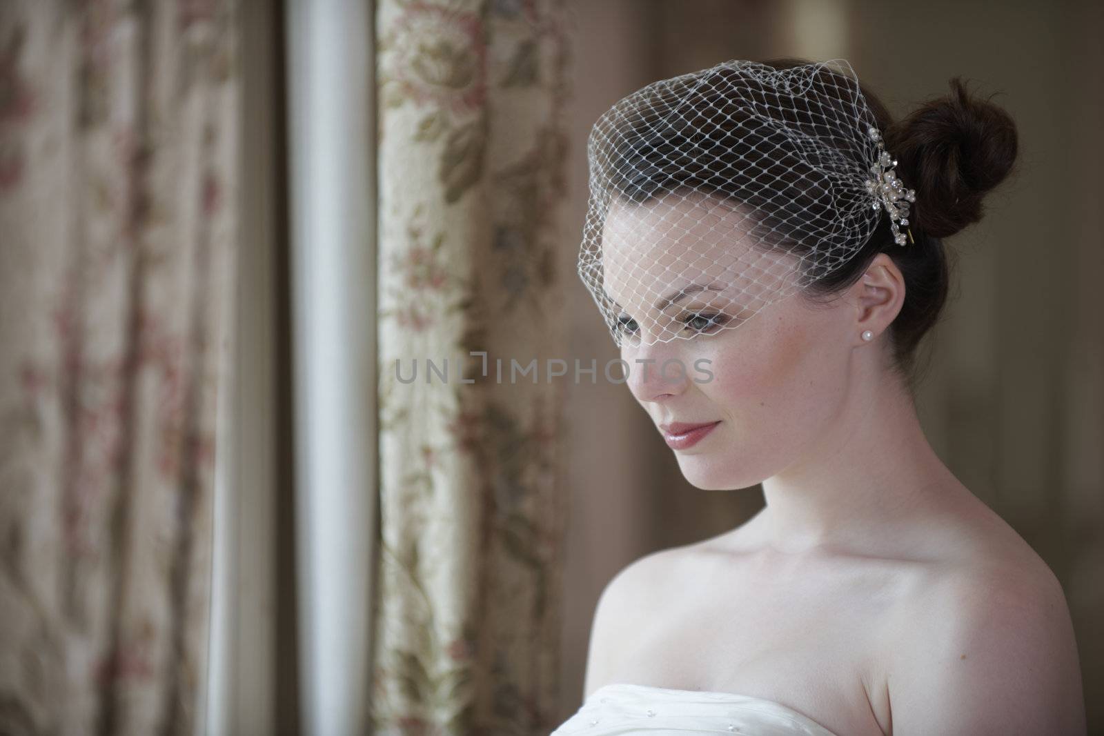 Pretty bride looking out of window and smiling on her wedding day