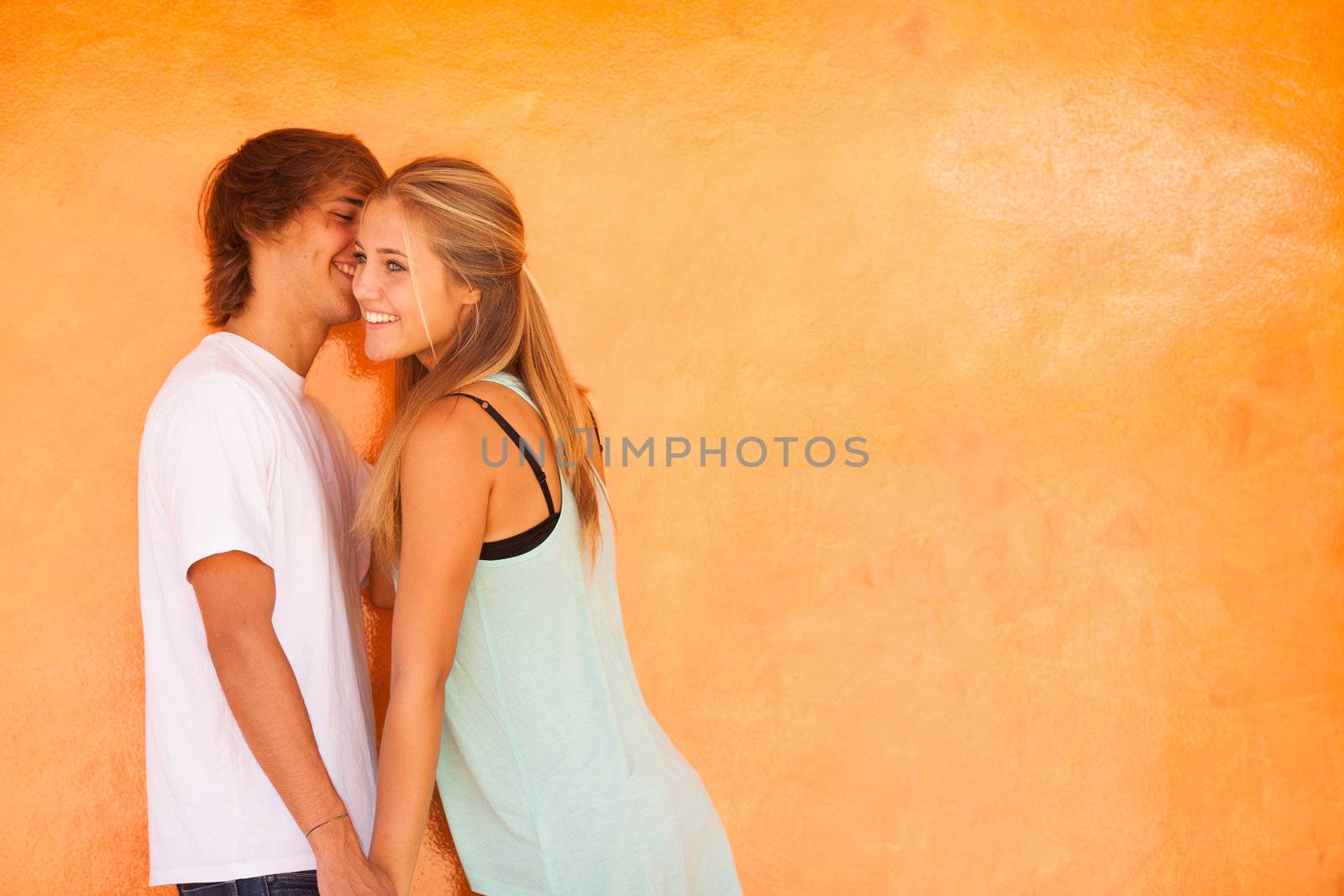 Young beautiful couple having great time over orange background