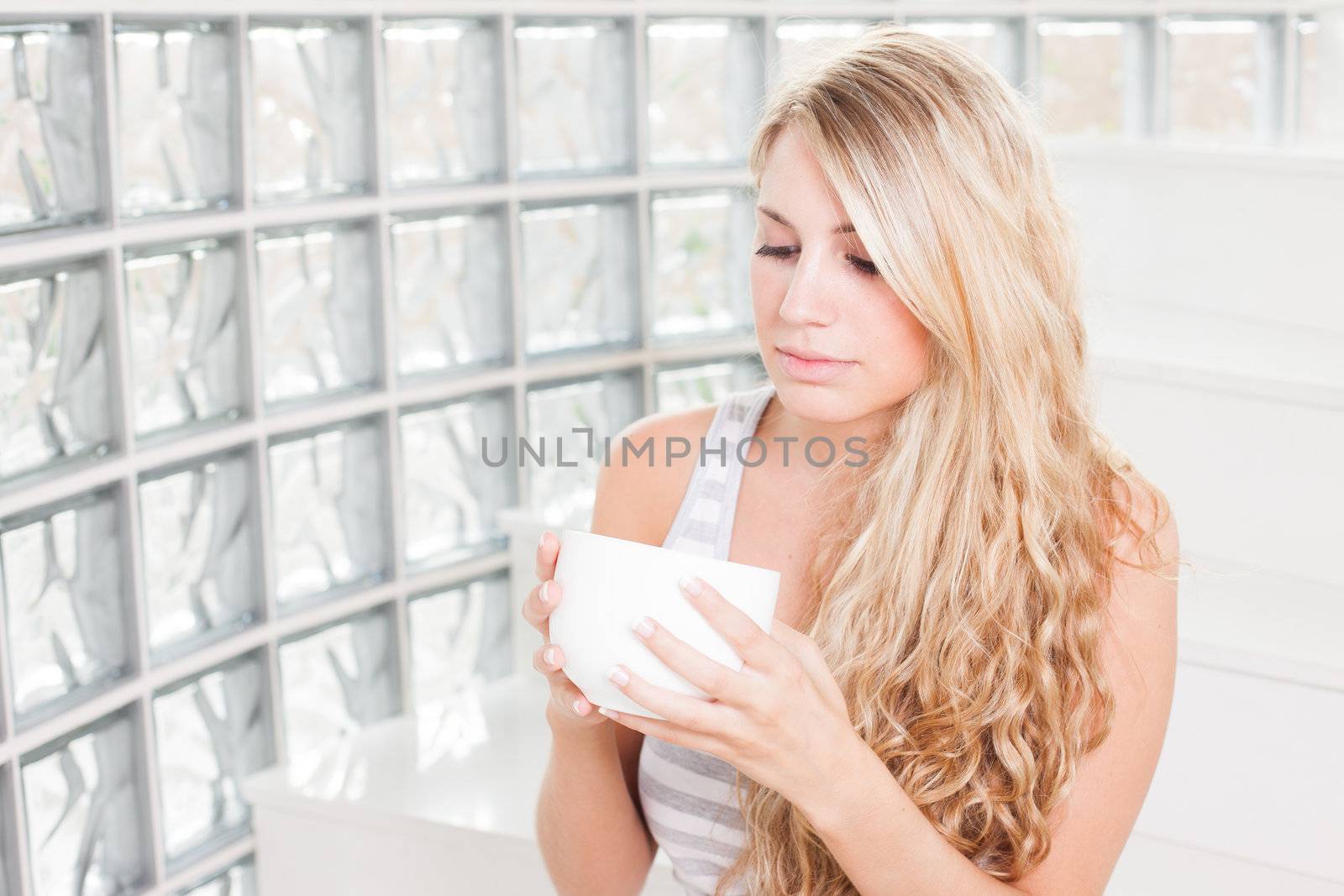 young beautiful woman drinks coffee on white cup