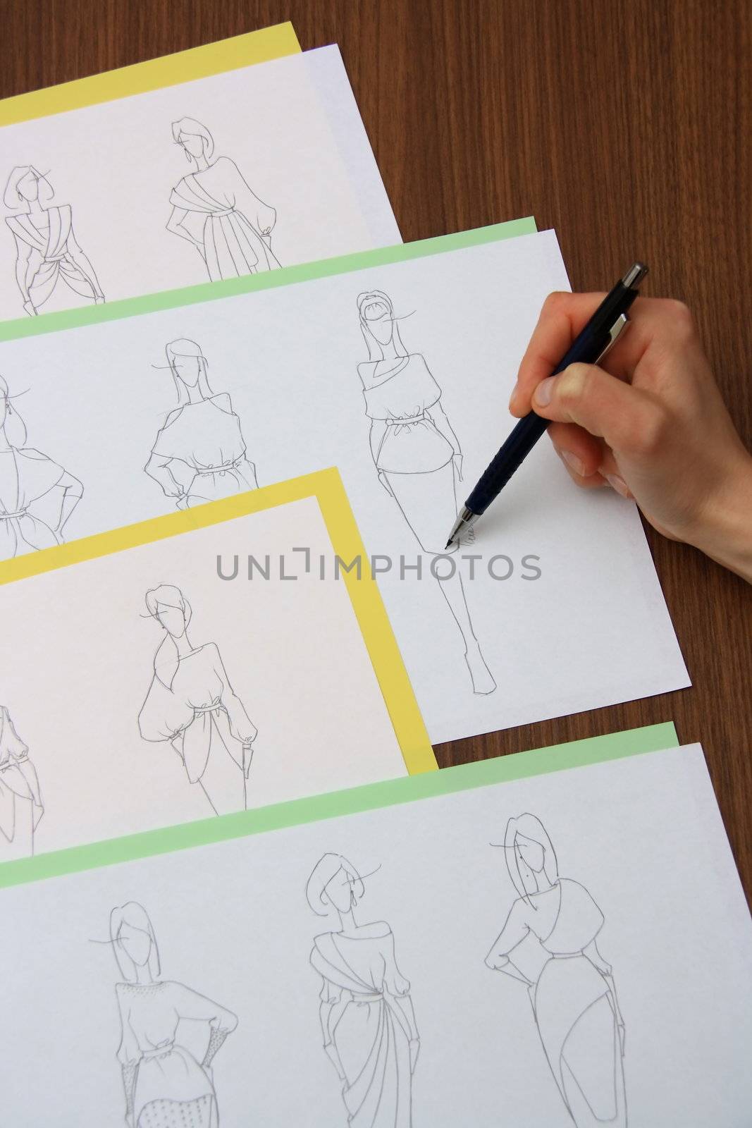 designer assessing fashion drawings on the collection of clothes