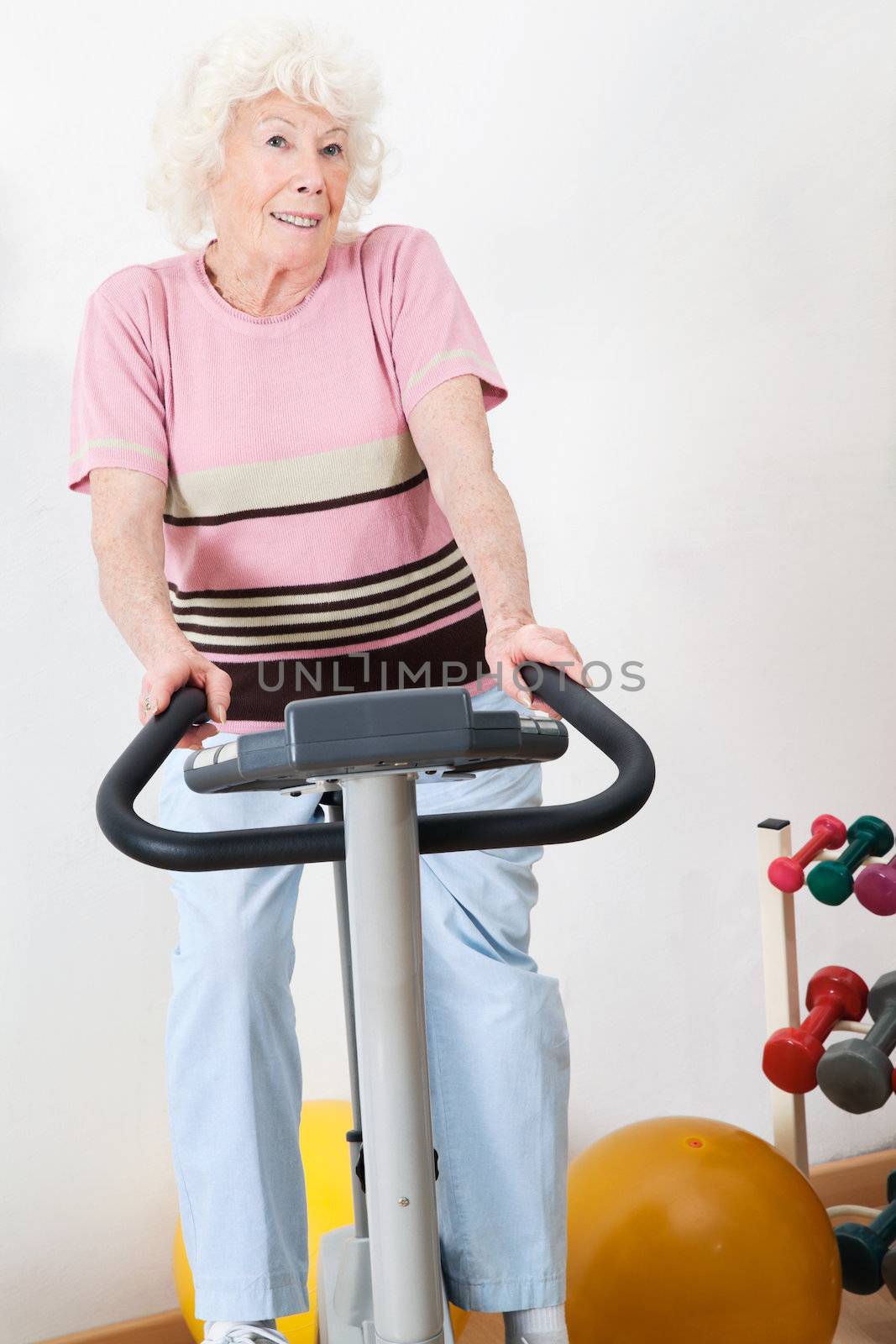 Portrait of a happy senior woman exercising on bike in gym
