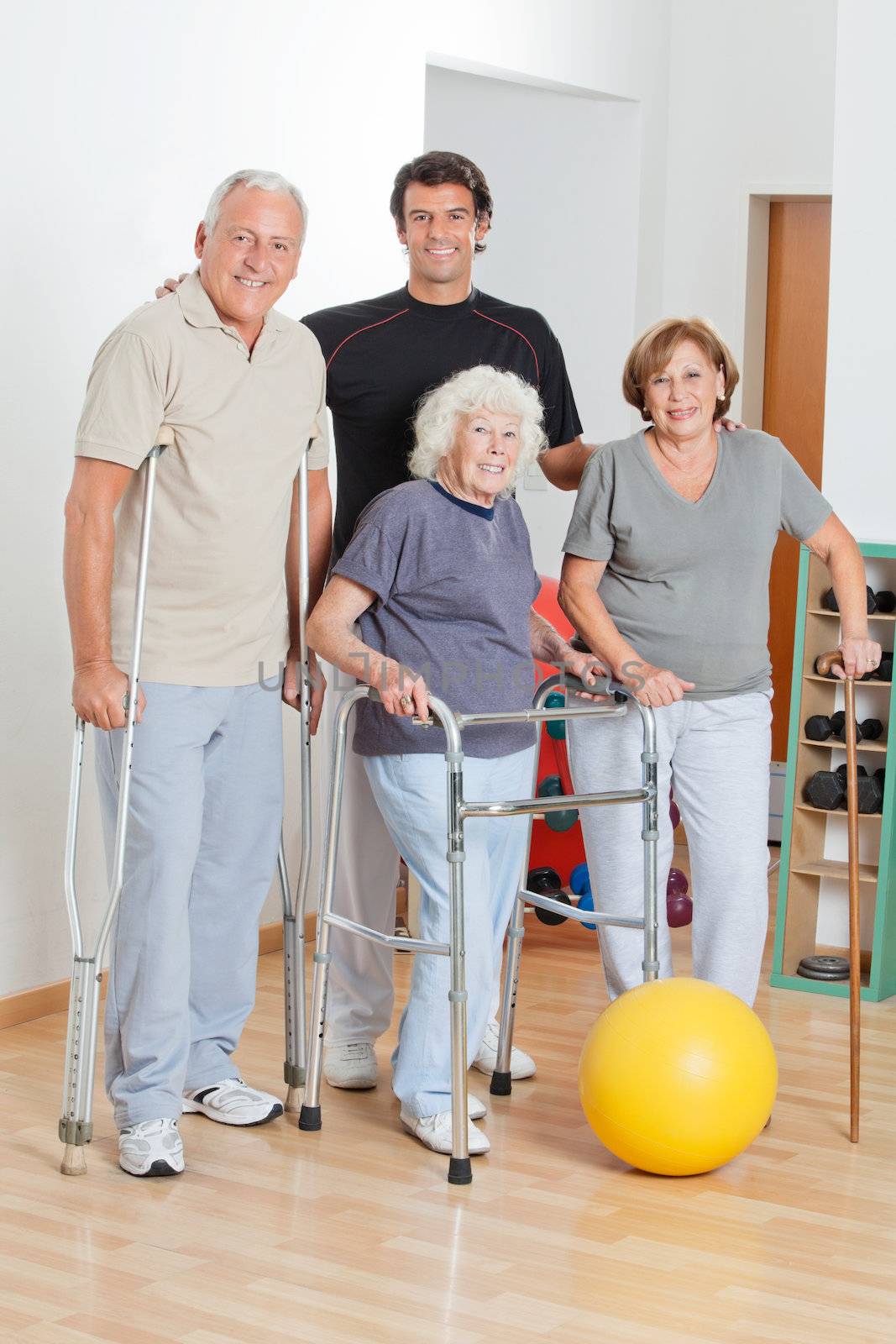 Full length happy portrait of disabled senior people with trainer