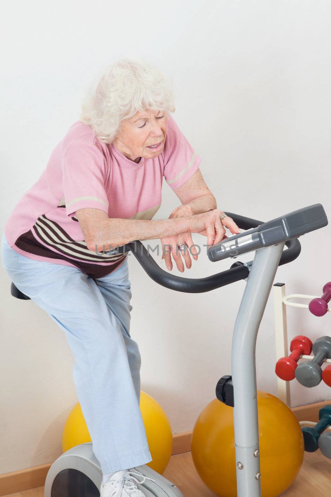 Tired Senior Woman Exercising On Bike by leaf