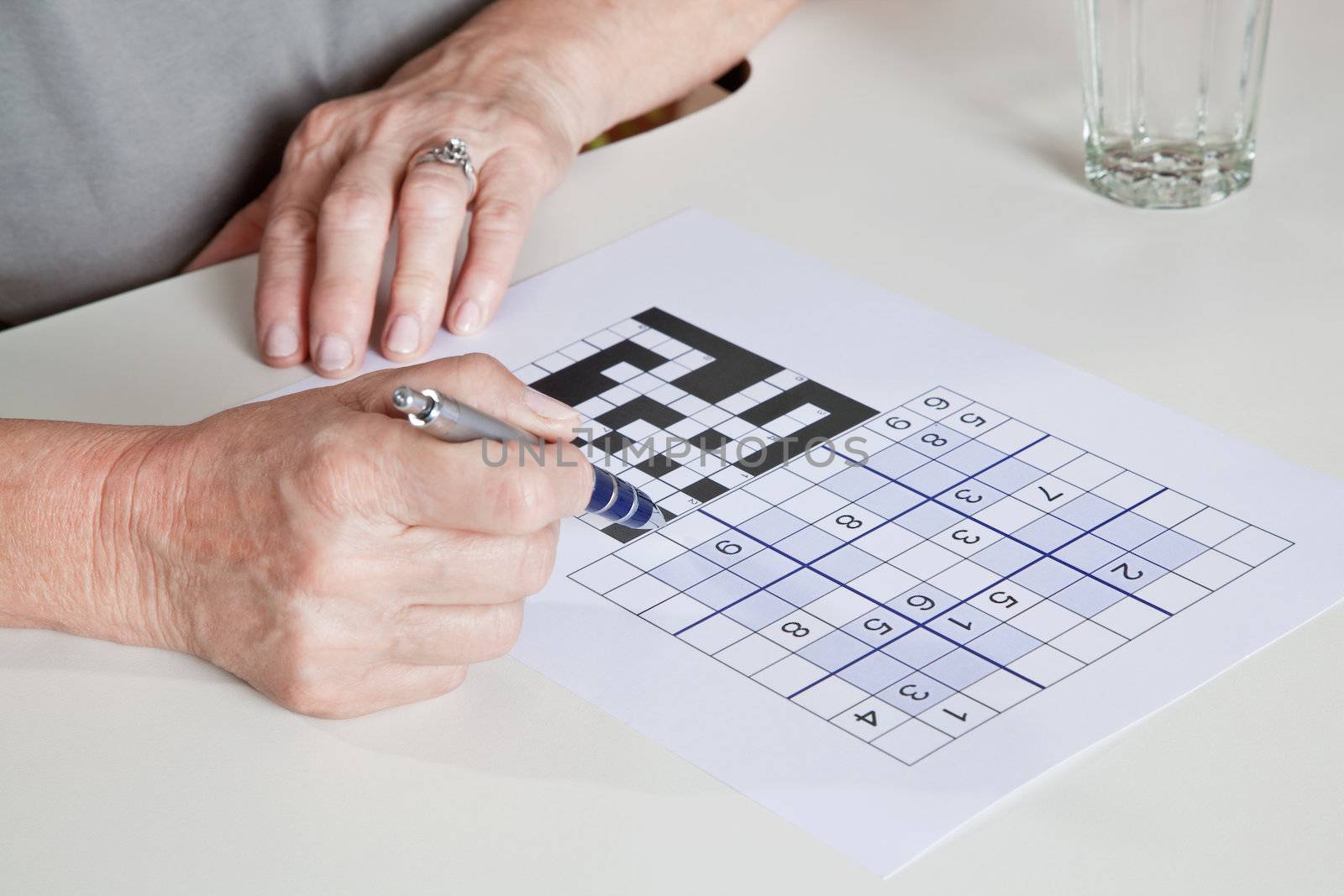 Mature Woman playing Sudoku Puzzle by leaf