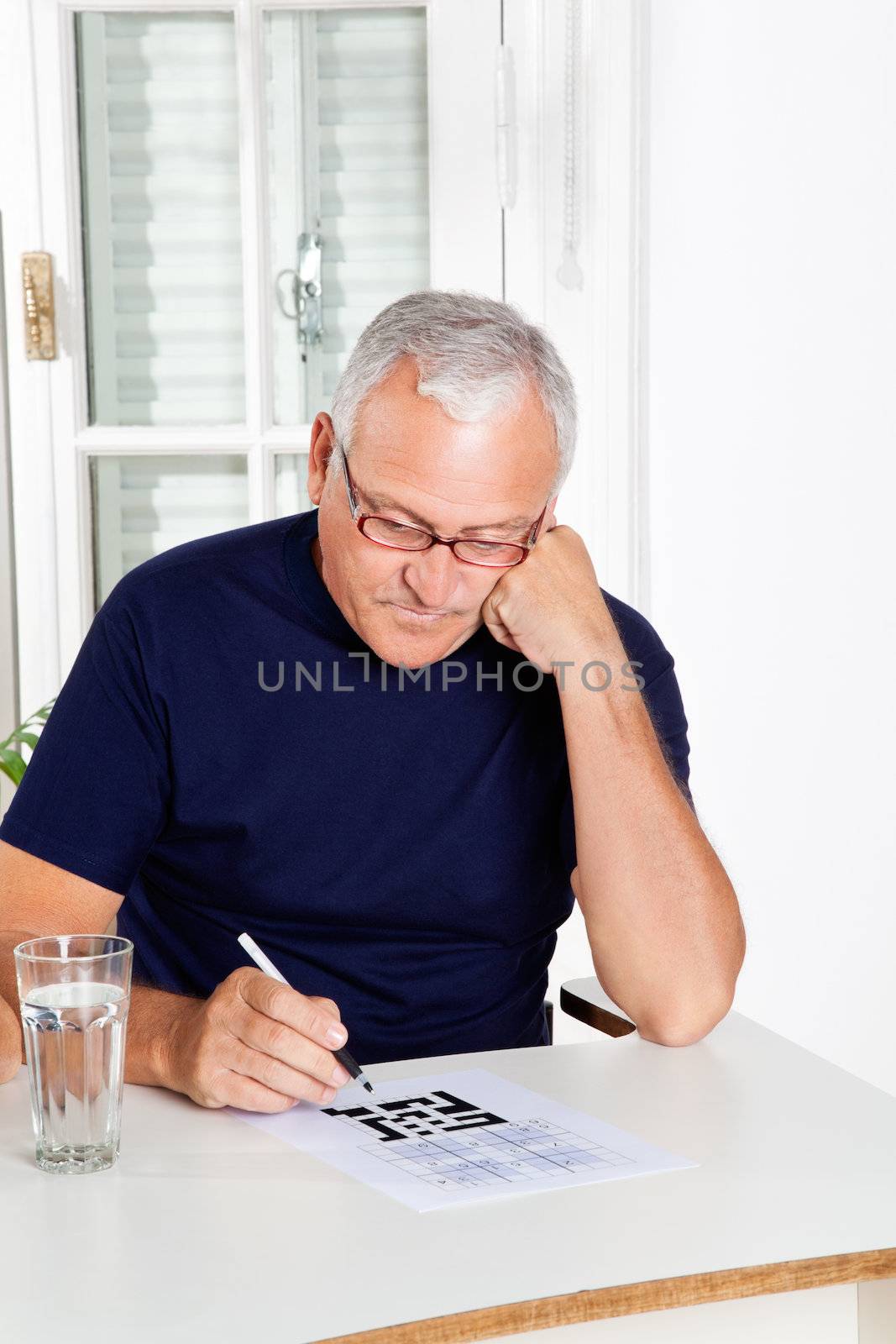 Senior man playing leisure games with glass of water in foreground