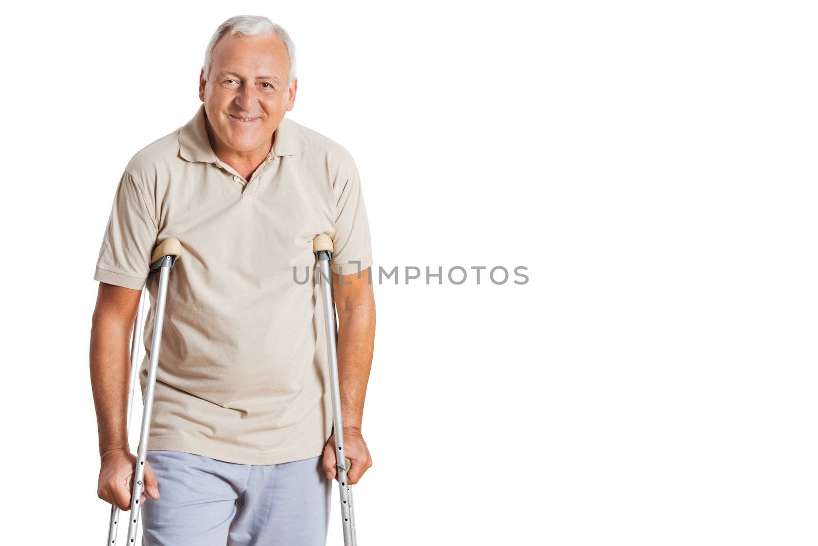 Portrait of smiling senior man on crutches standing over white background.