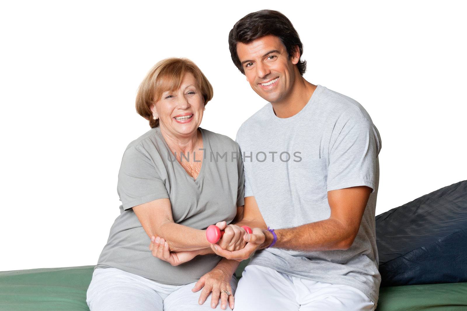 Portrait of happy young therapist giving muscle training for elbow joint over white background