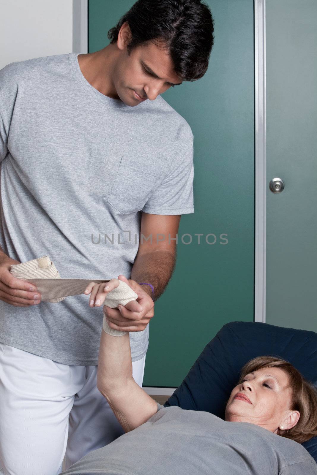 Therapist applying bandage on the hand.