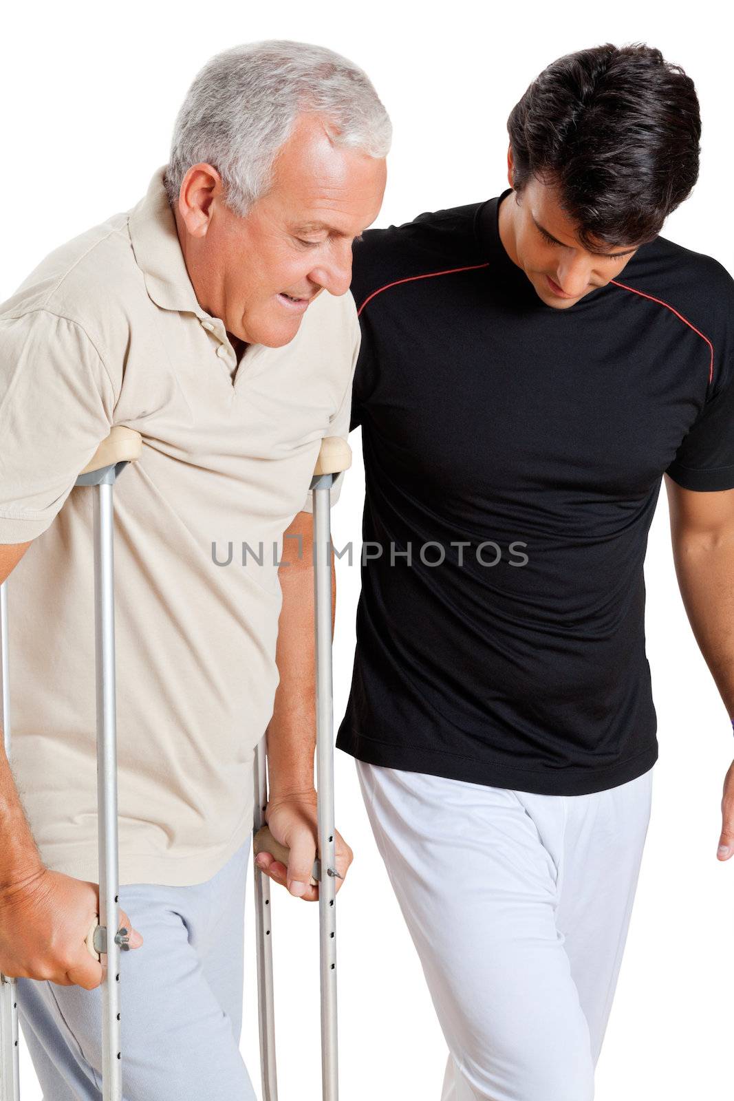 Trainer helping senior man with crutches to walk over white background