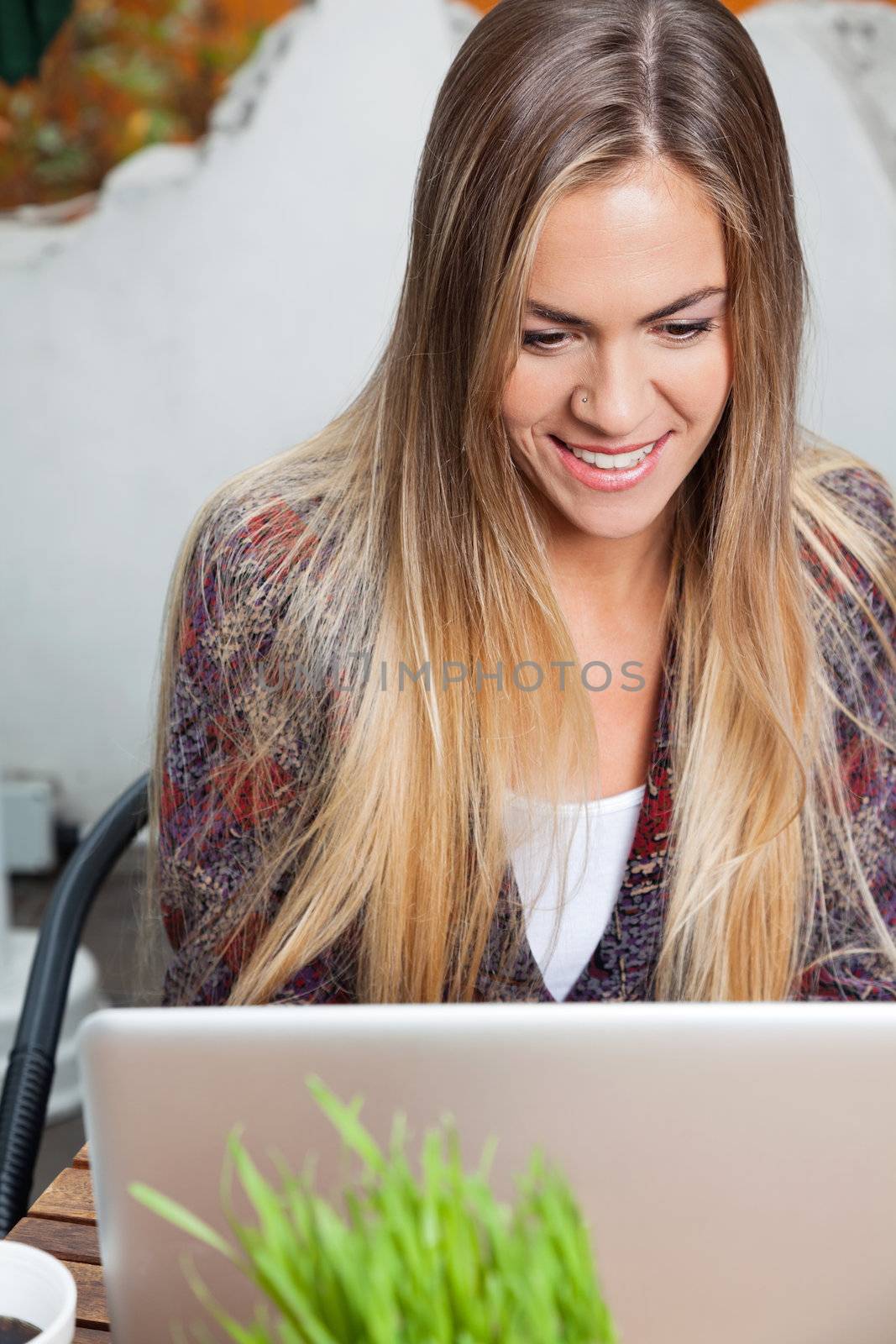 Woman Using Laptop in Cafe by leaf