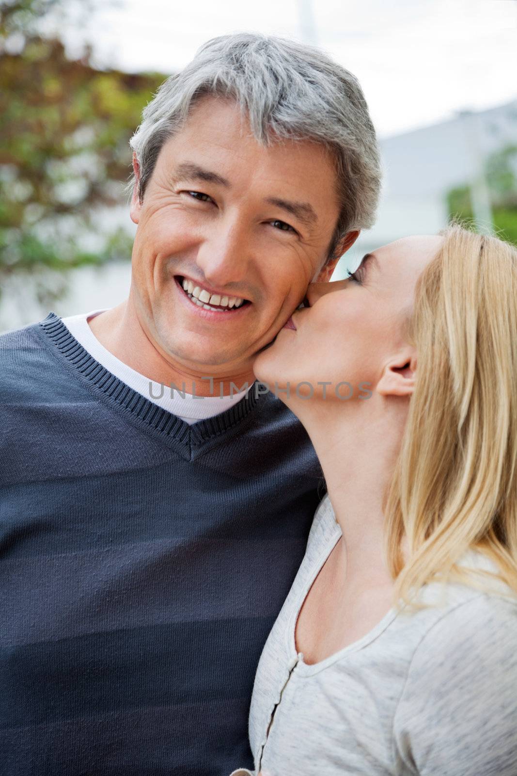 Blond woman kissing a cheerful middle aged man