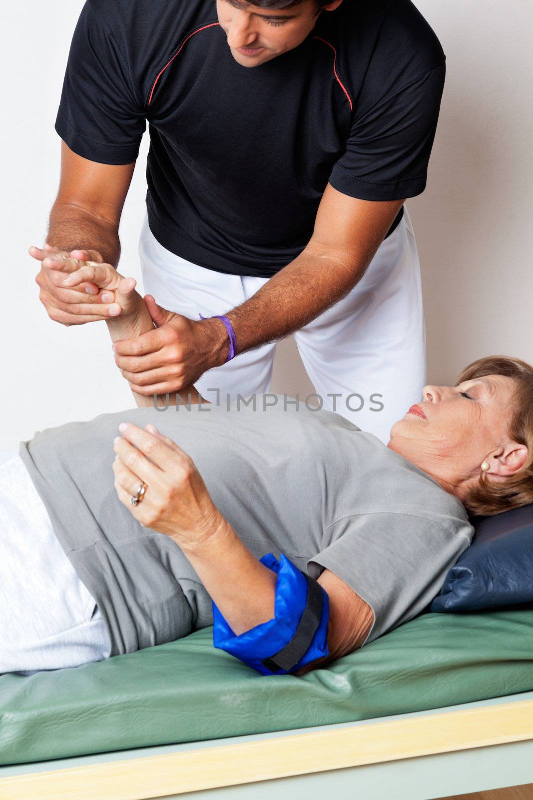 Young therapist examining senior woman's hand